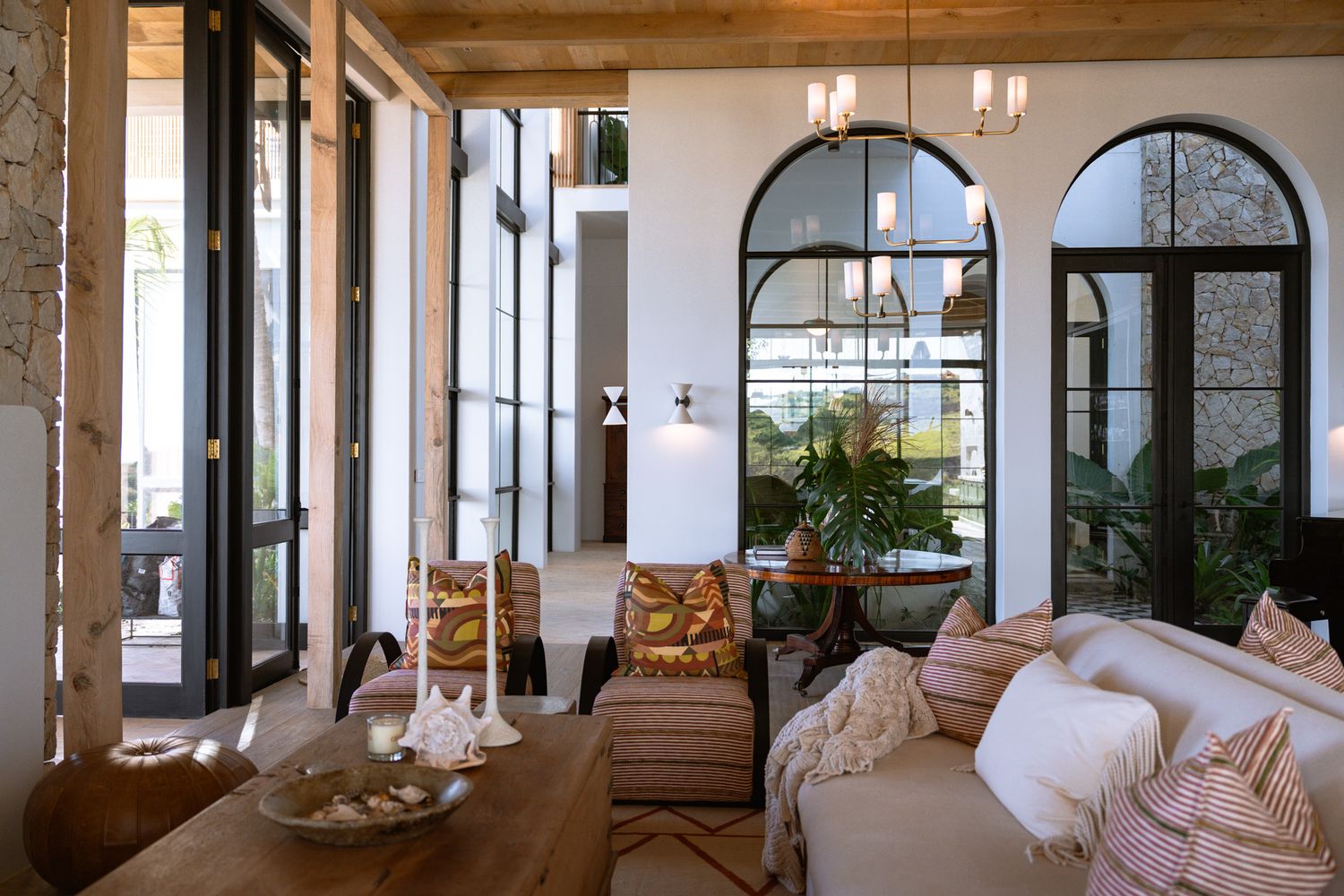 Mediterranean-style interior with arched windows, white walls, and wooden beam ceilings overlooking the ocean.