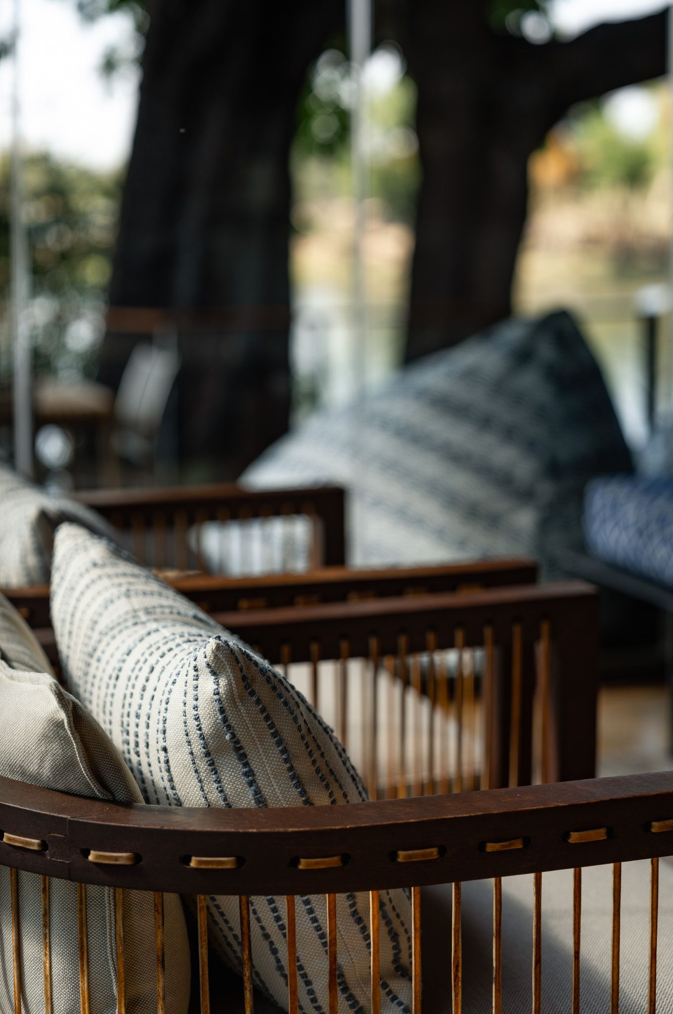 Rattan outdoor furniture with striped cushions in natural lighting.