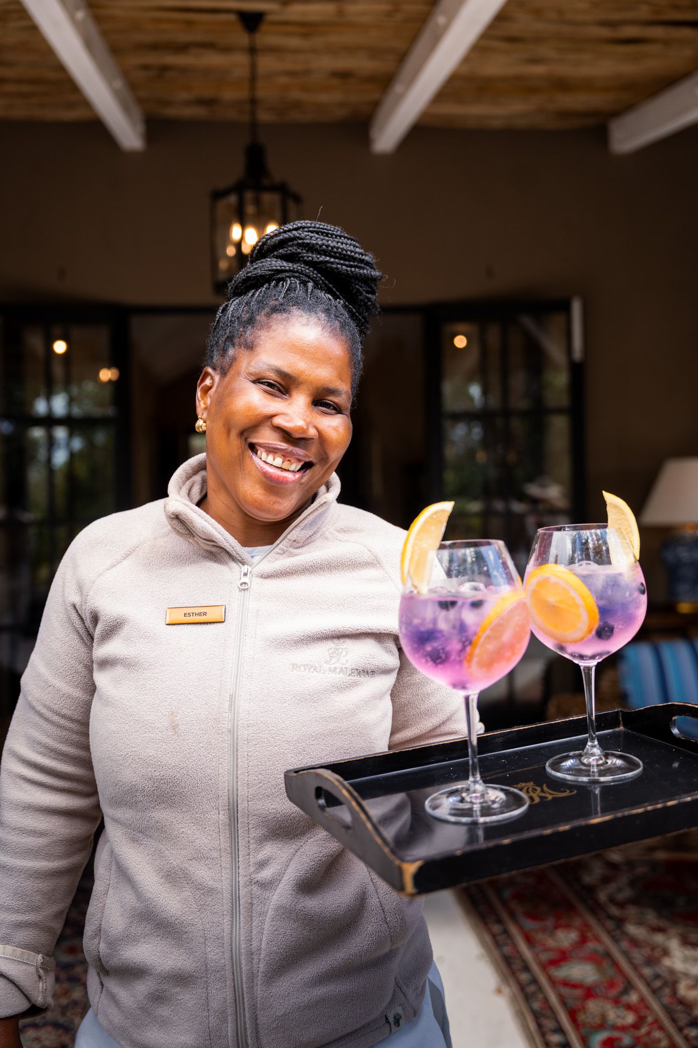 Staff member displaying colorful cocktails on a serving tray at a luxury lodge.