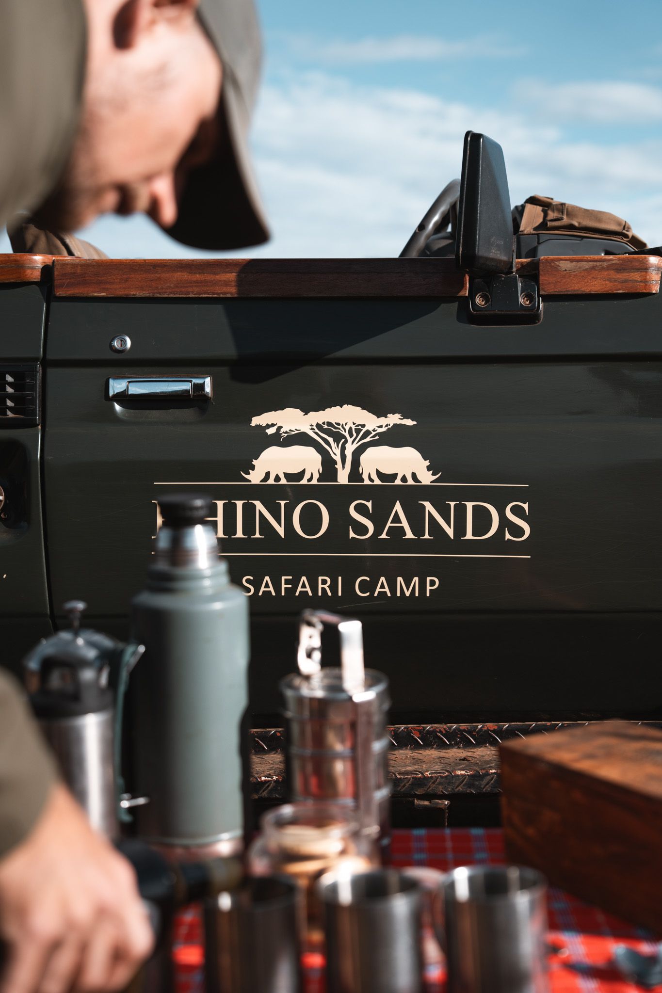 Close-up of Rhino Sands Safari Camp logo on vehicle with camping equipment.