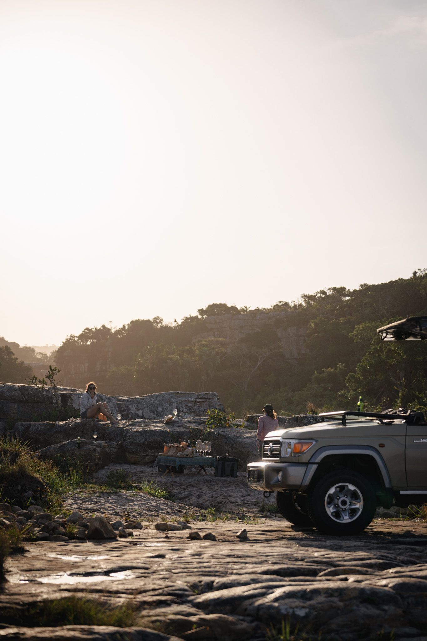 Vehicles parked on rocky overlook during sunset safari excursion.