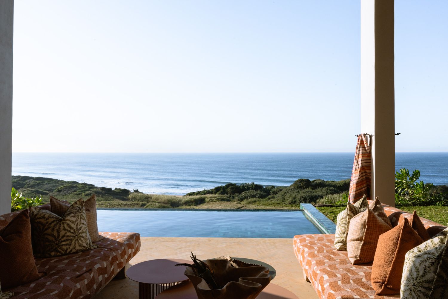 Luxurious oceanfront lounge area with infinity pool overlooking coastal views.