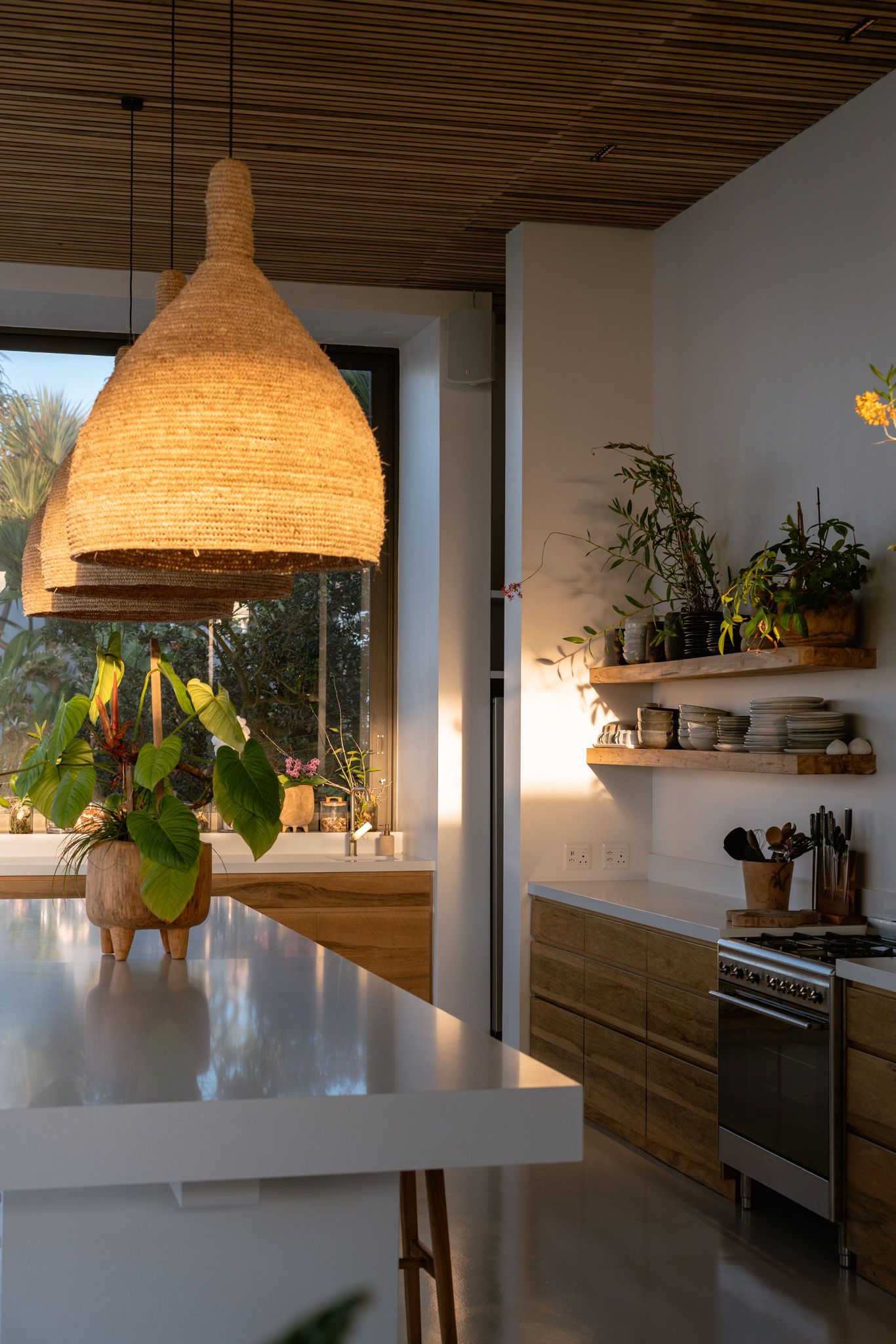 Sunlit modern kitchen with large woven pendant light and wooden cabinetry.