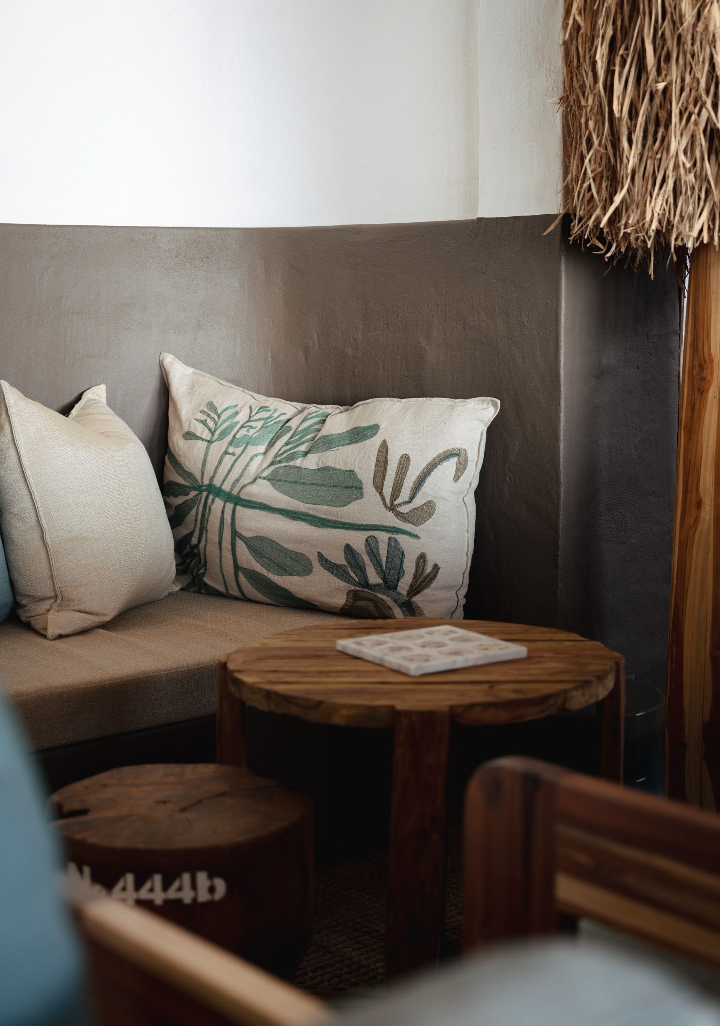 Cozy corner seating with tropical leaf-print pillows and wooden accent table.
