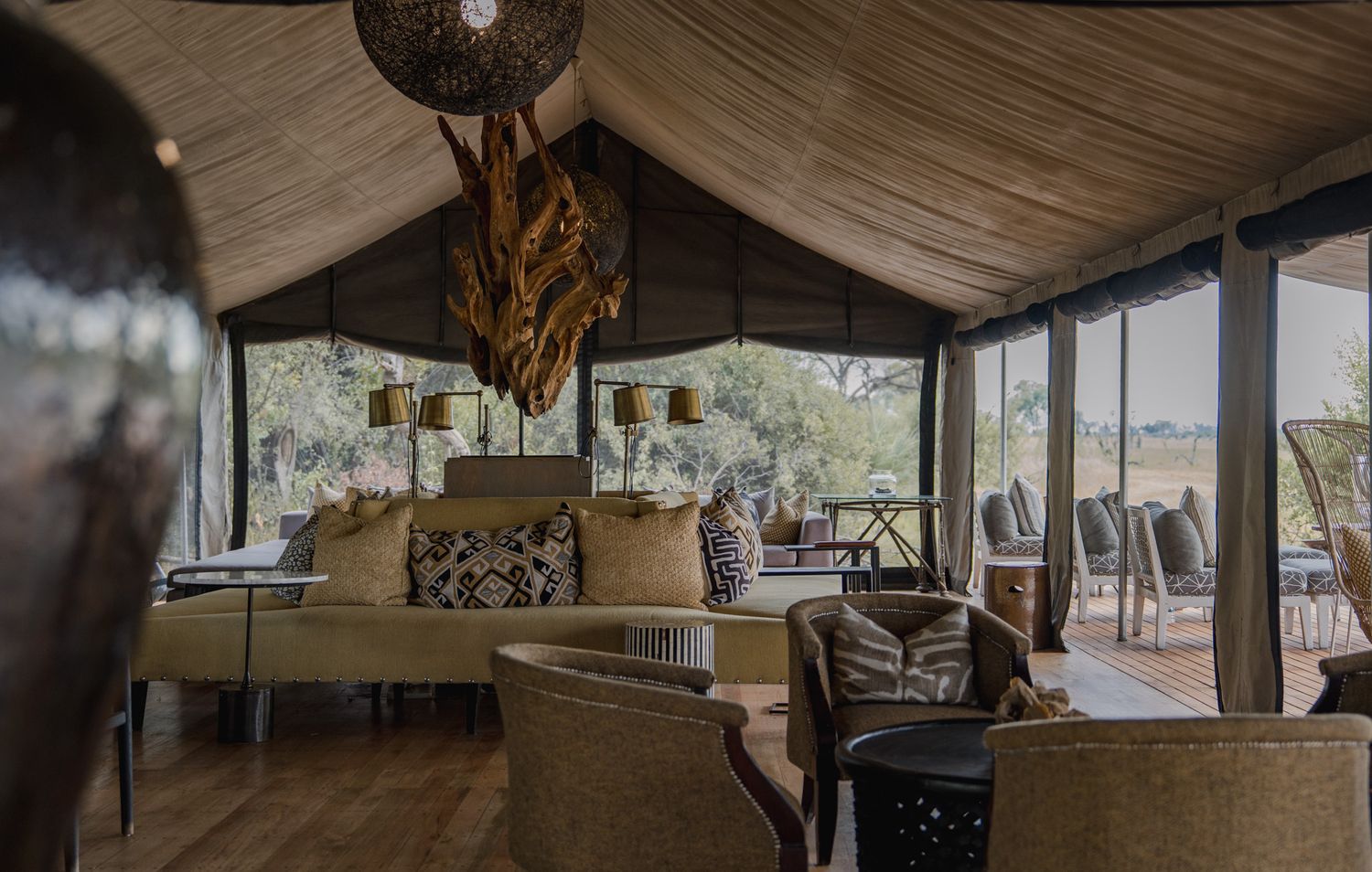 Interior view of a luxury tent with wooden beams and canvas roof showing rustic glamping accommodations.