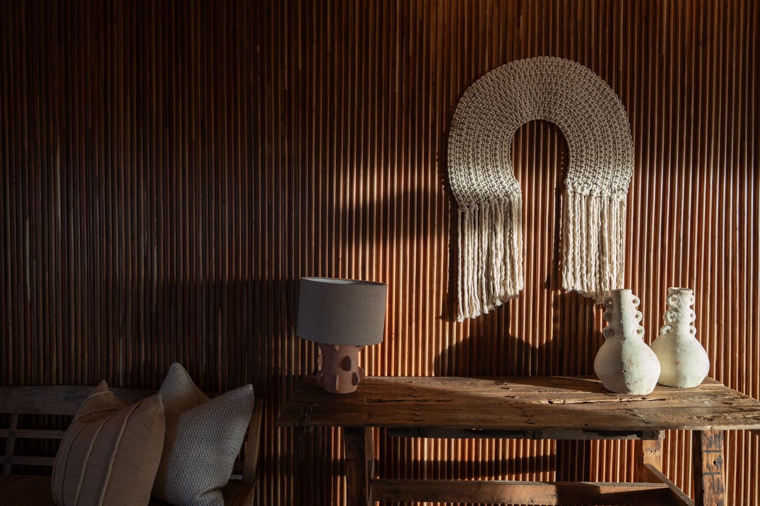 Modern living space with wood paneling and macrame wall art in warm lighting.