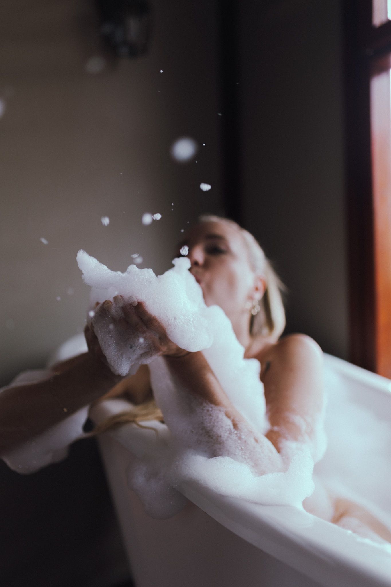 Person blowing bubbles while relaxing in a luxurious bathtub.