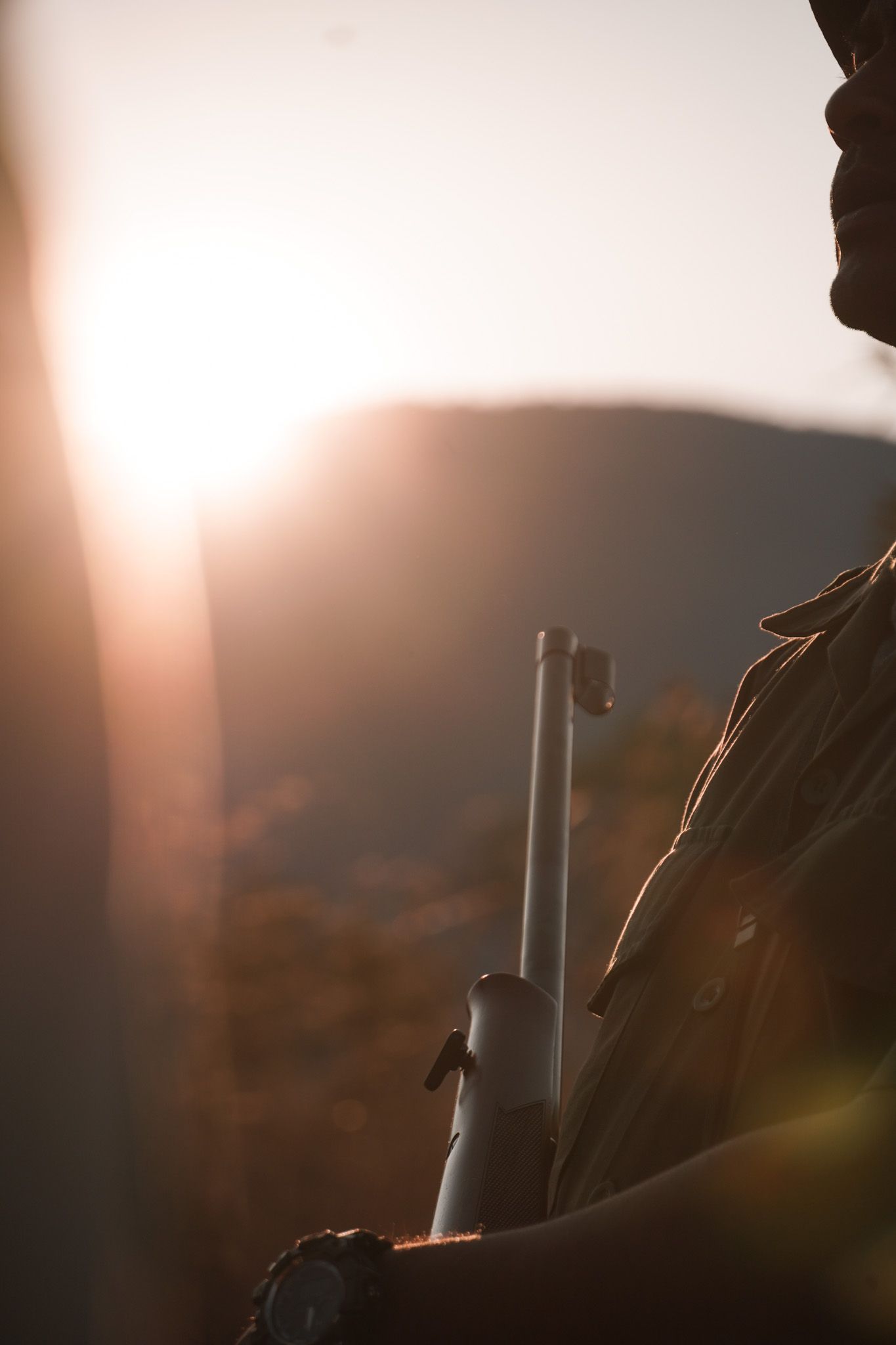 Silhouetted figures against a hazy sunset backdrop in mountains.