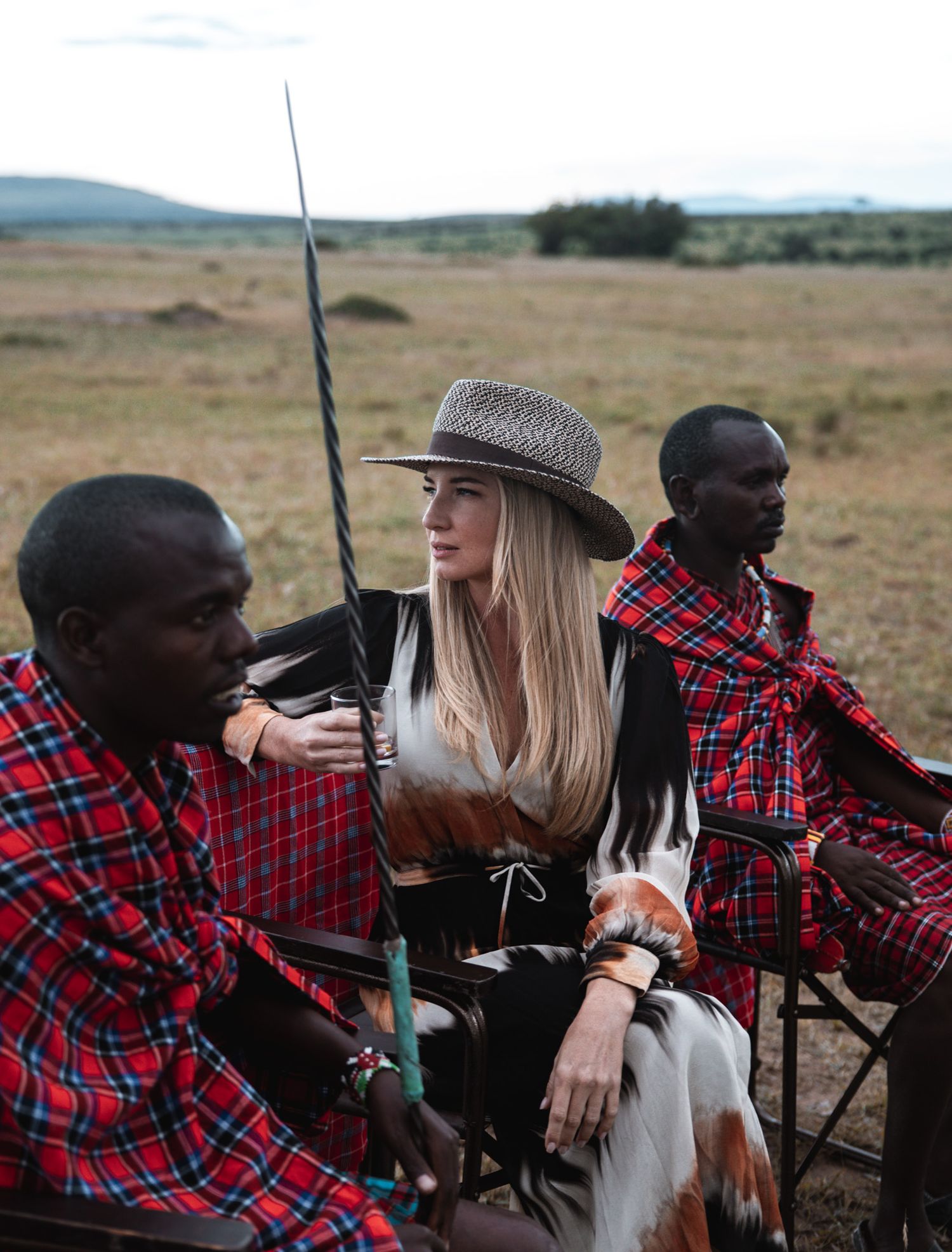 Traditional Maasai guides in red checkered clothing sharing stories during a safari excursion.