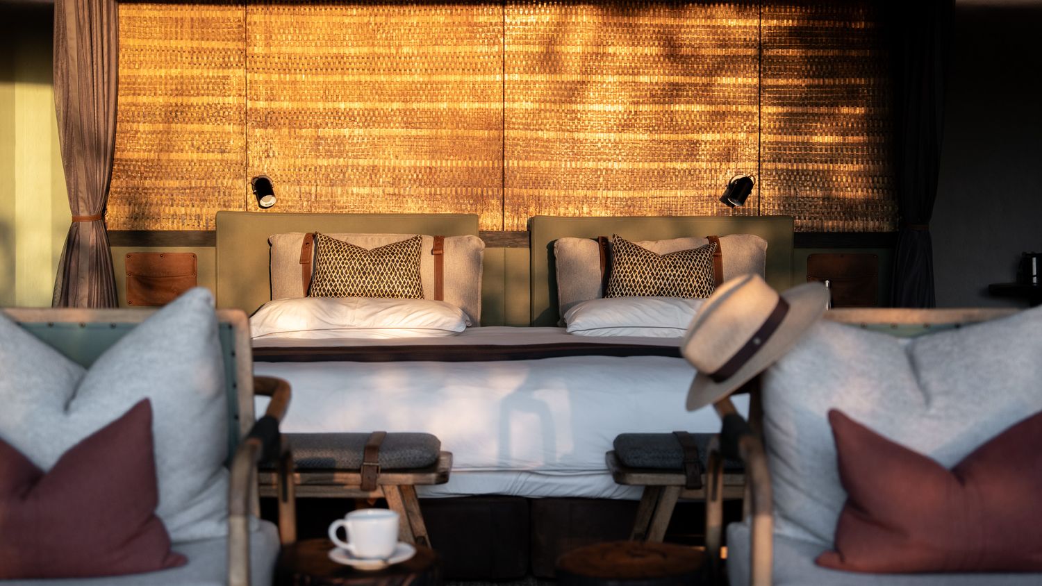 Hotel room interior with exposed brick wall and soft furnishings in warm lighting.