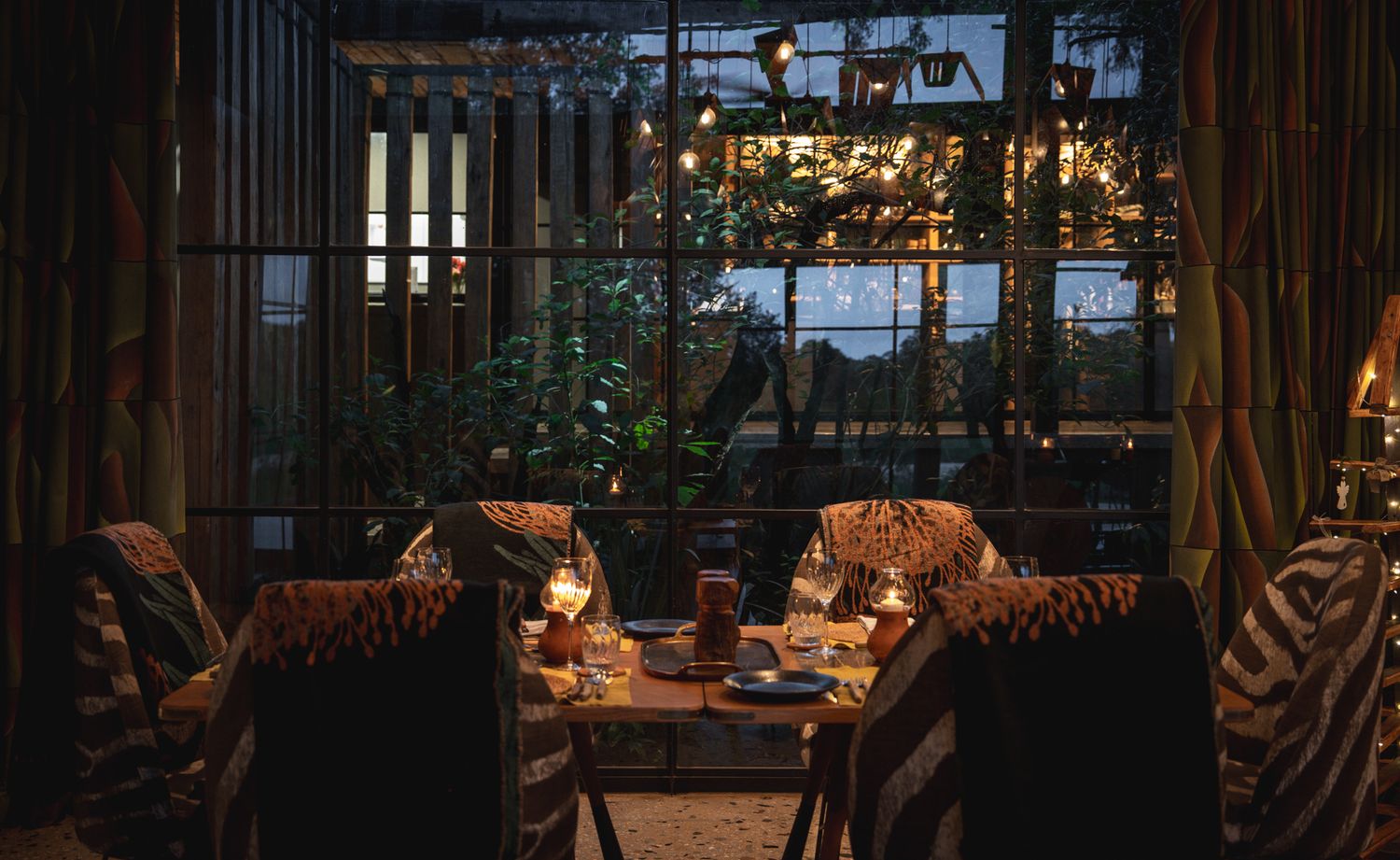 Cozy restaurant seating area with bamboo screens and warm ambient lighting at dusk.
