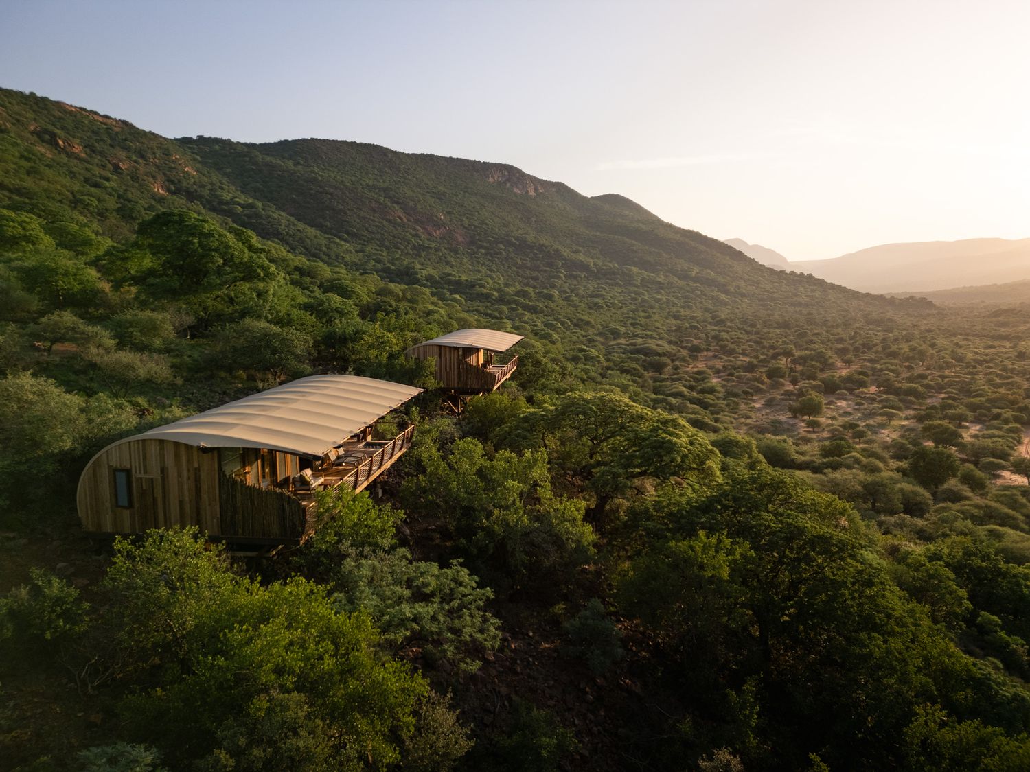 Contemporary wooden lodge built into mountainside with panoramic valley views.