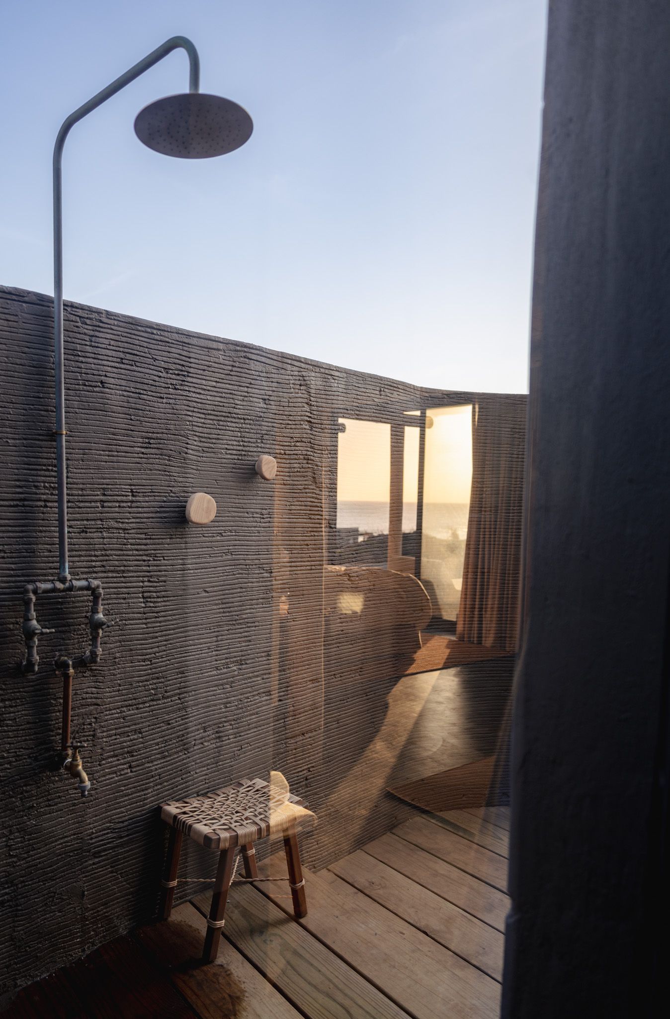 Modern deck space with textured walls and wooden flooring bathed in warm sunlight.