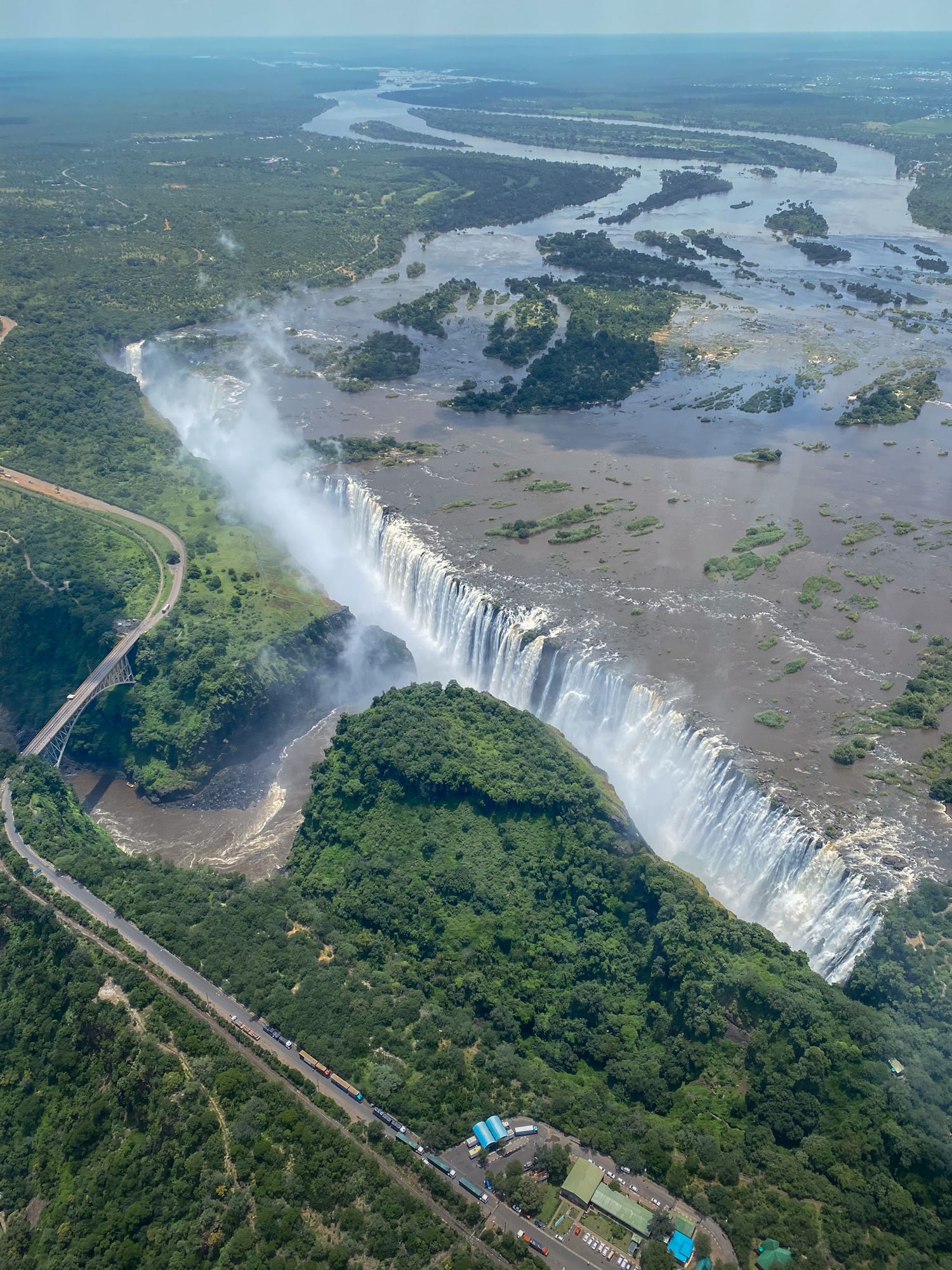 Aerial view of Victoria Falls thundering down into the gorge surrounded by lush vegetation.