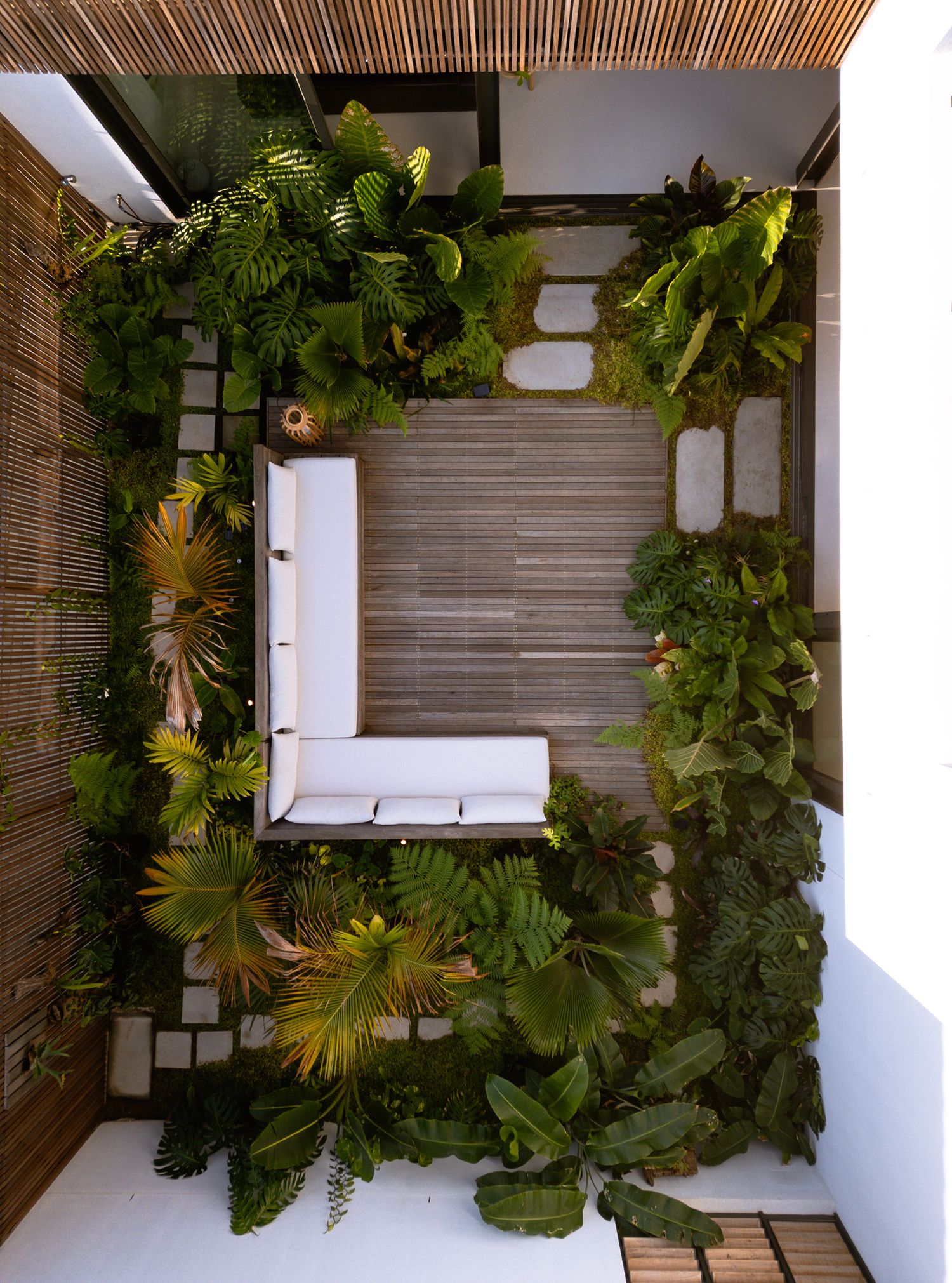 Overhead view of modern patio space with white seating and tropical landscaping.
