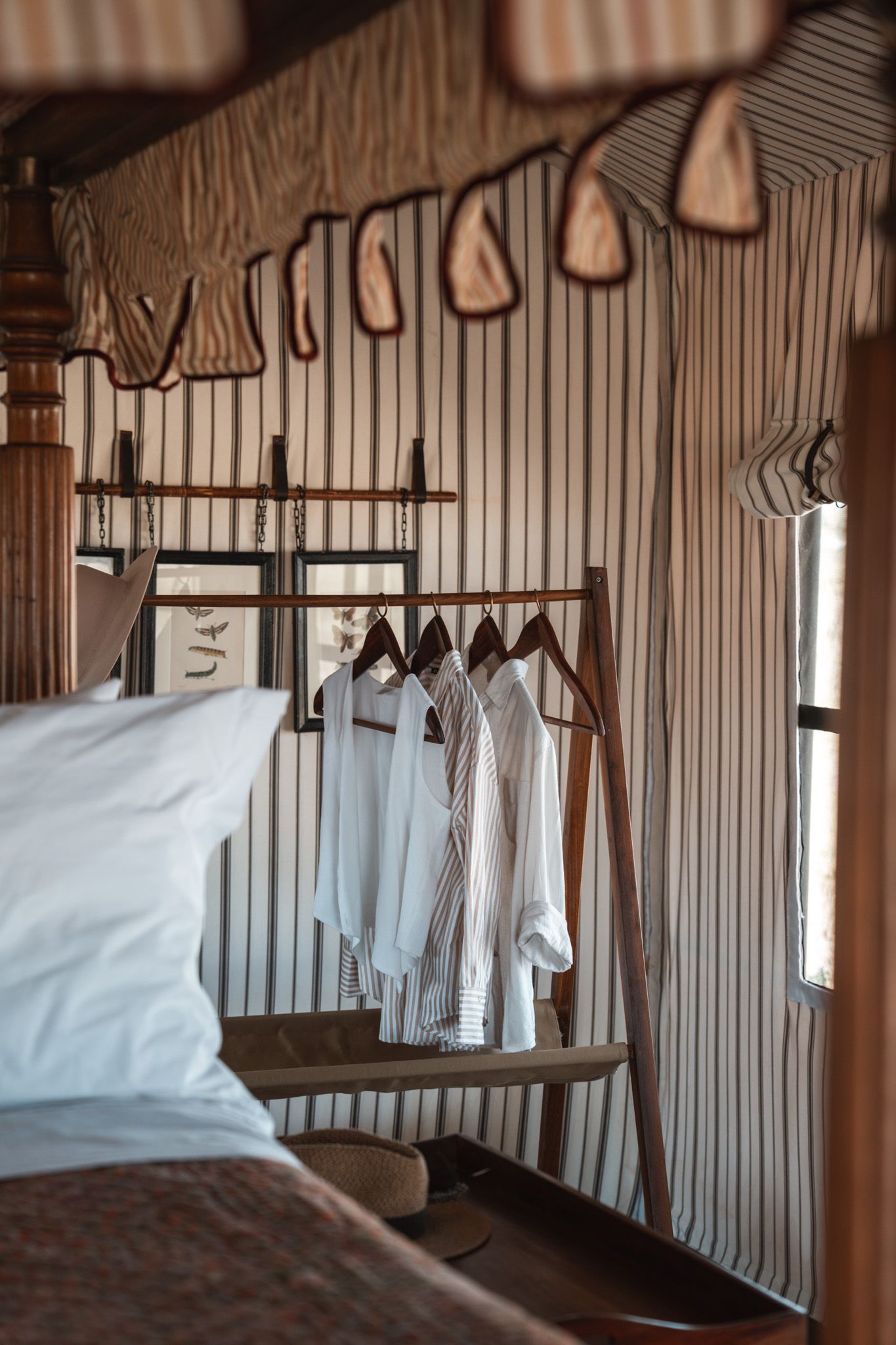 A row of crisp white garments hanging neatly in a rustic closet with wooden walls.