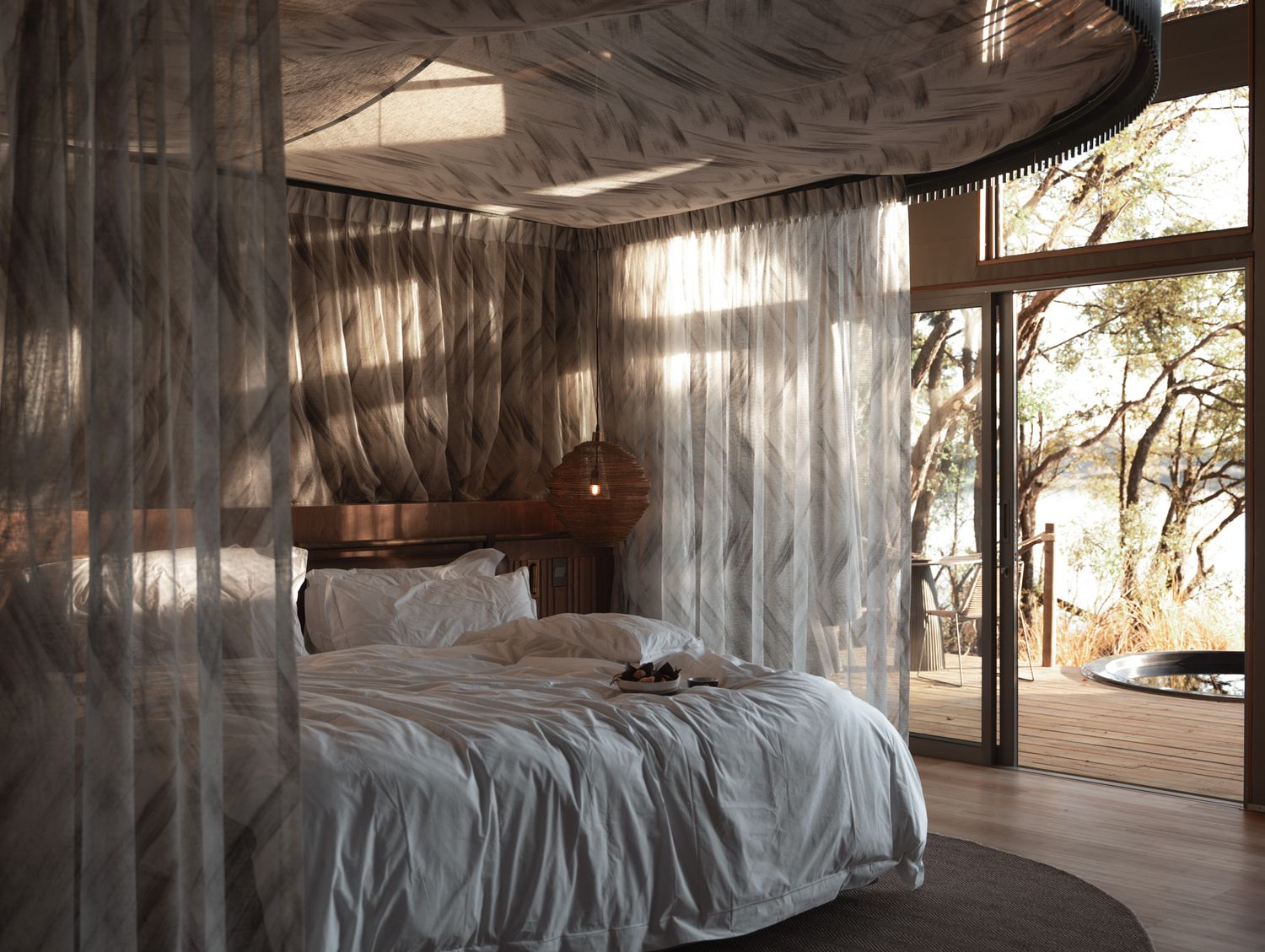 Romantic bedroom with flowing sheer curtains and natural light streaming through windows.