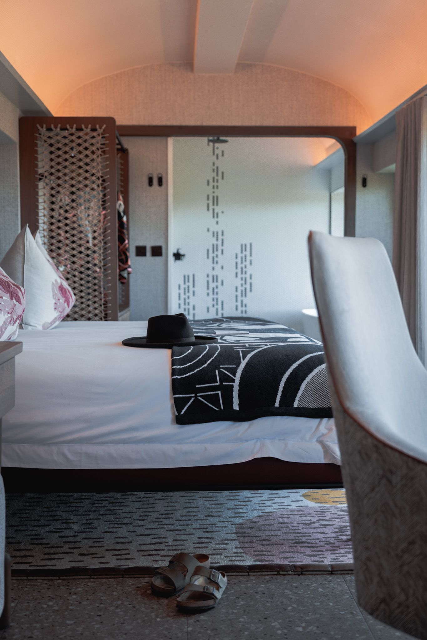 Modern hotel room interior with contemporary bedding and geometric wall patterns.