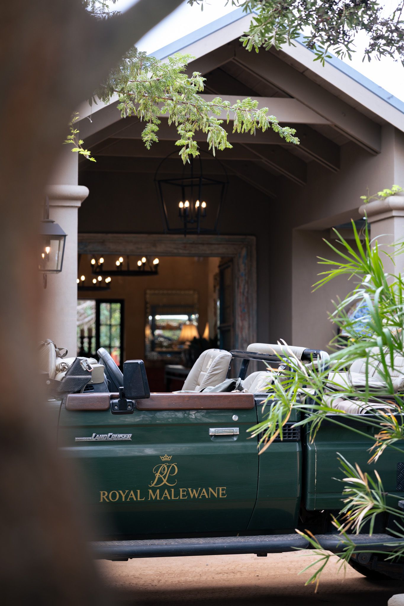 Royal Malewane safari vehicle parked under a covered outdoor area with green foliage.