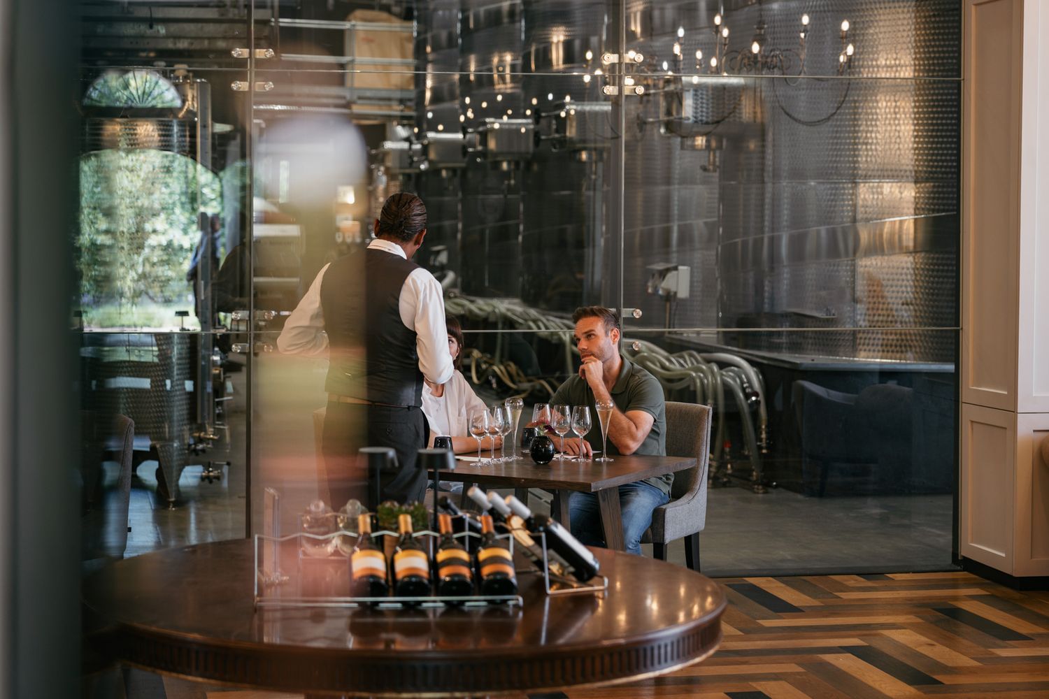 Interior of an elegant restaurant with chandelier lighting and patrons at a curved bar.
