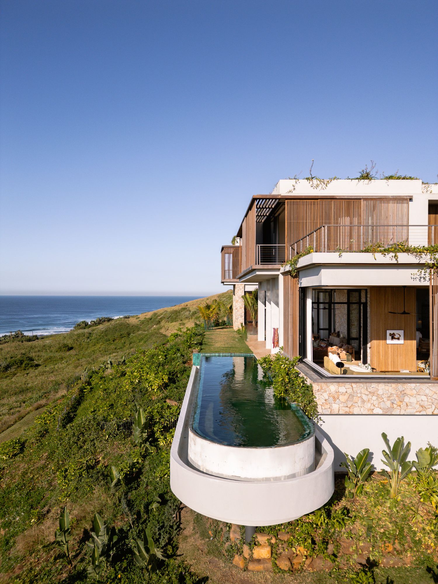 Contemporary oceanfront home featuring a curved infinity pool and modern architecture.