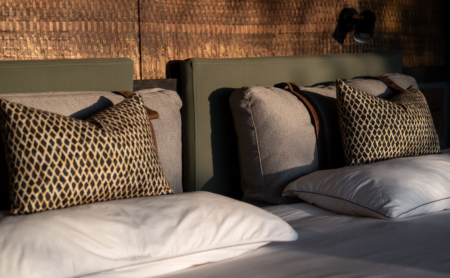 Cozy bedroom interior with decorative pillows and natural textures creating shadow patterns.