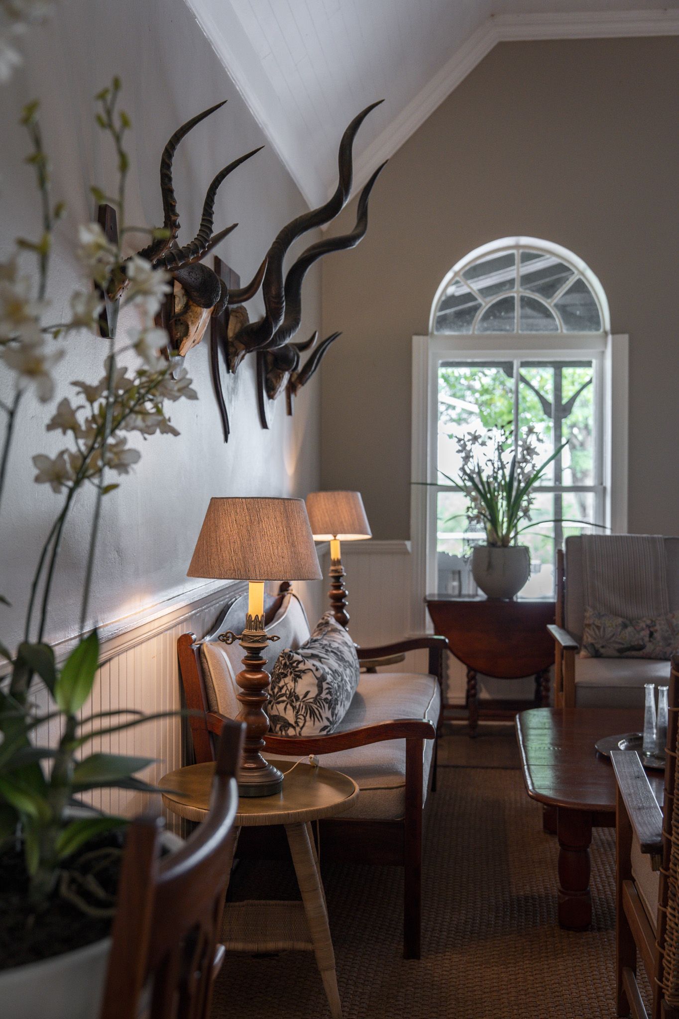 Elegant living room with arched window, antique furniture, and dramatic wall sculptures.