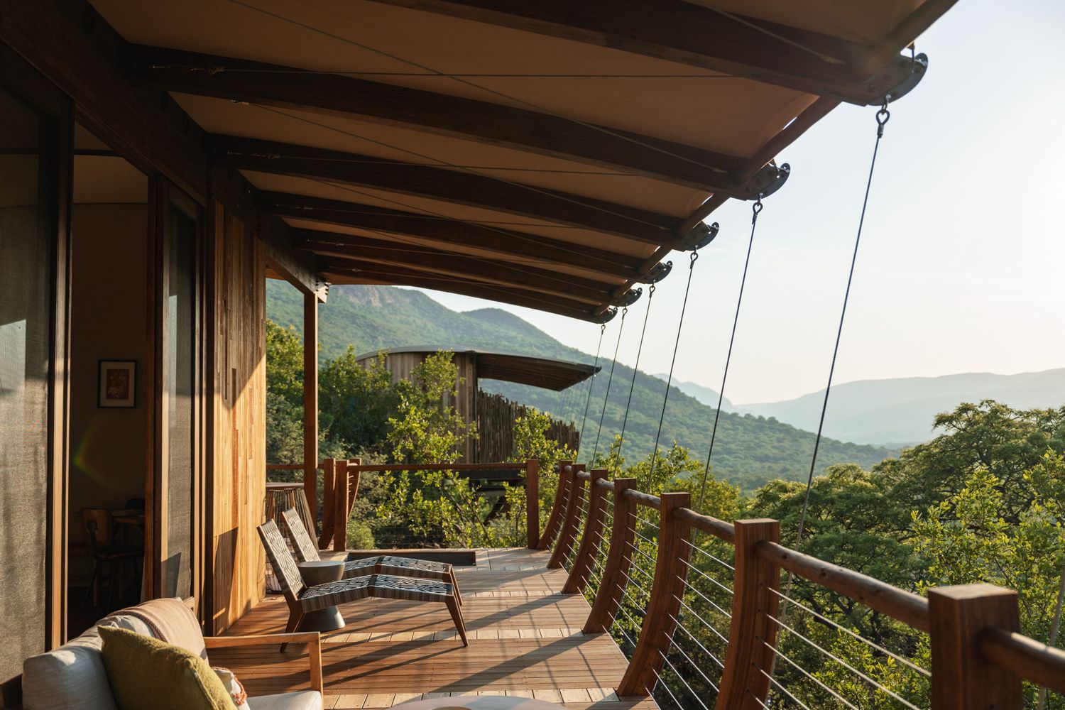 Covered terrace with contemporary outdoor furniture offering panoramic views of green mountains.