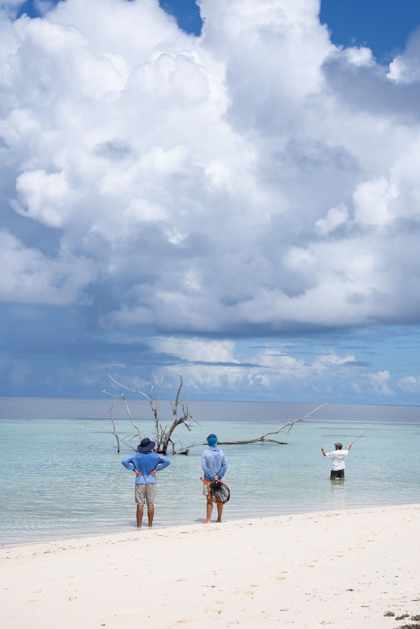 Fishermen casting lines on a pristine white sand beach with turquoise waters.