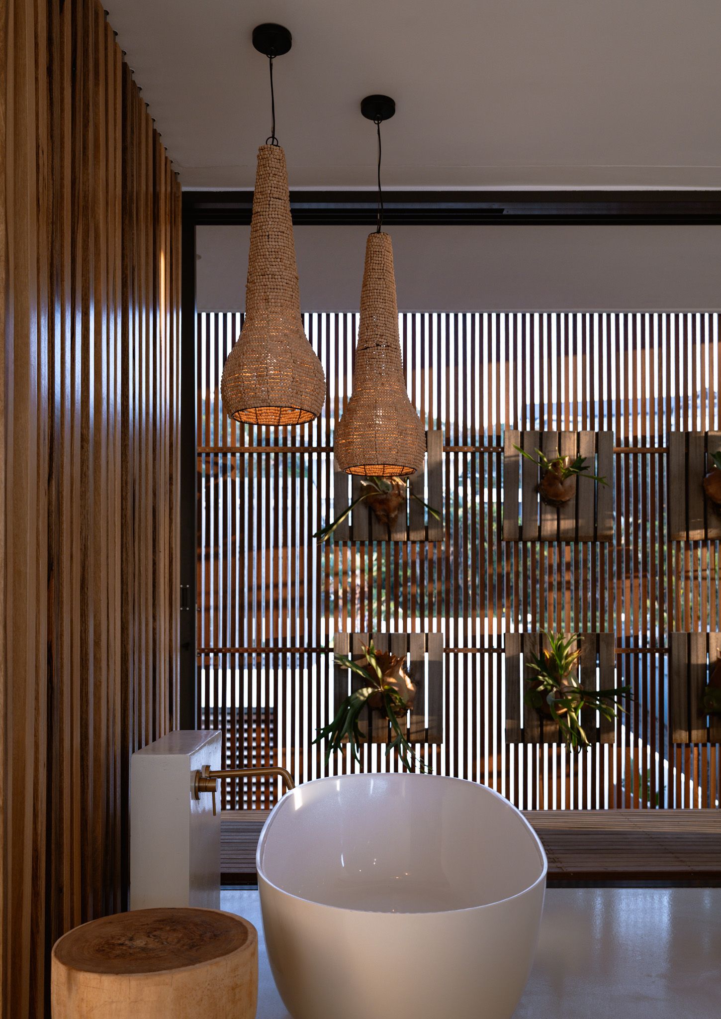 Modern bathroom featuring woven pendant lights and vertical wooden slats creating a natural screen.