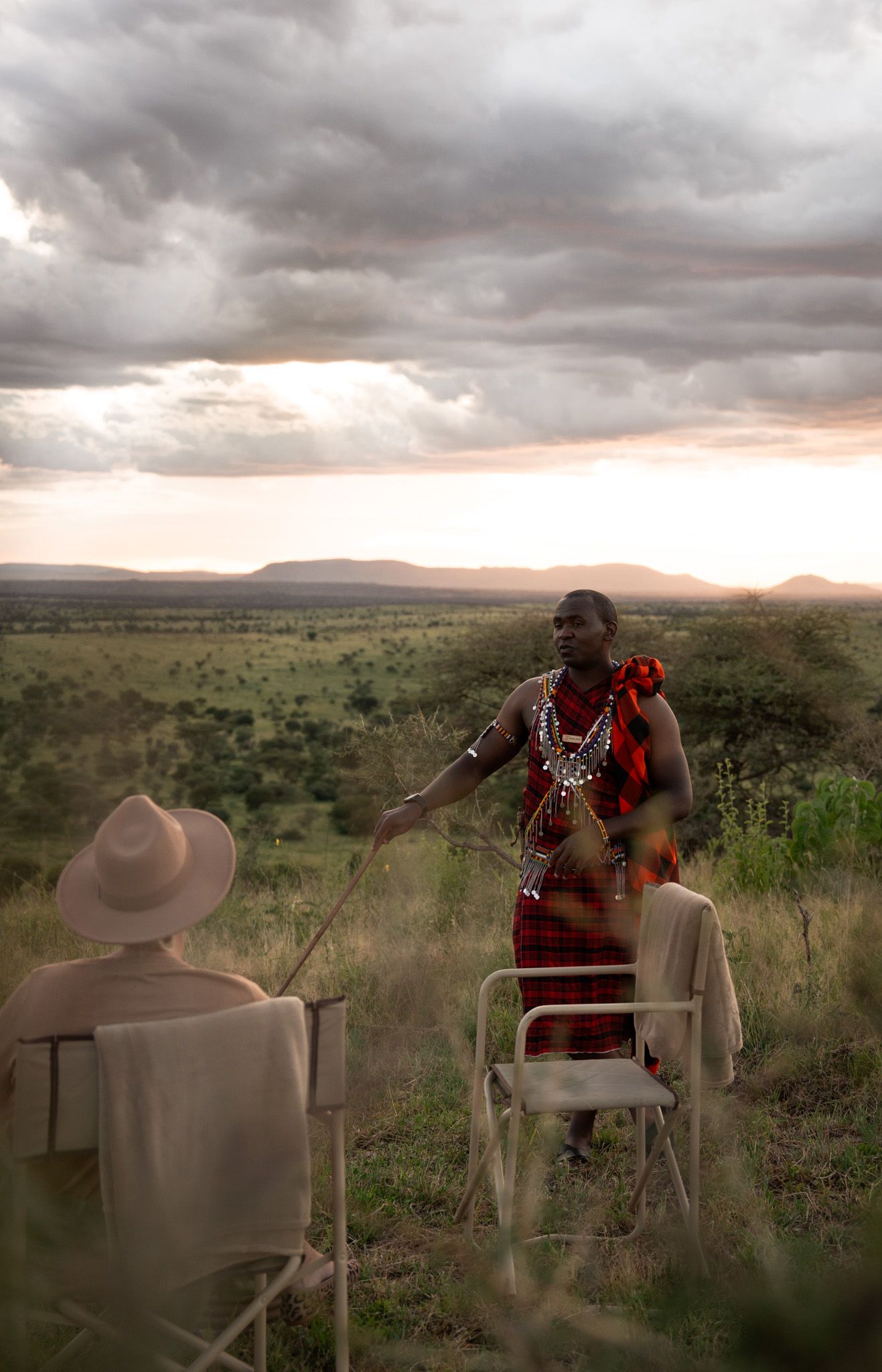 Safari camp chairs arranged at sunset overlooking African savanna landscape.