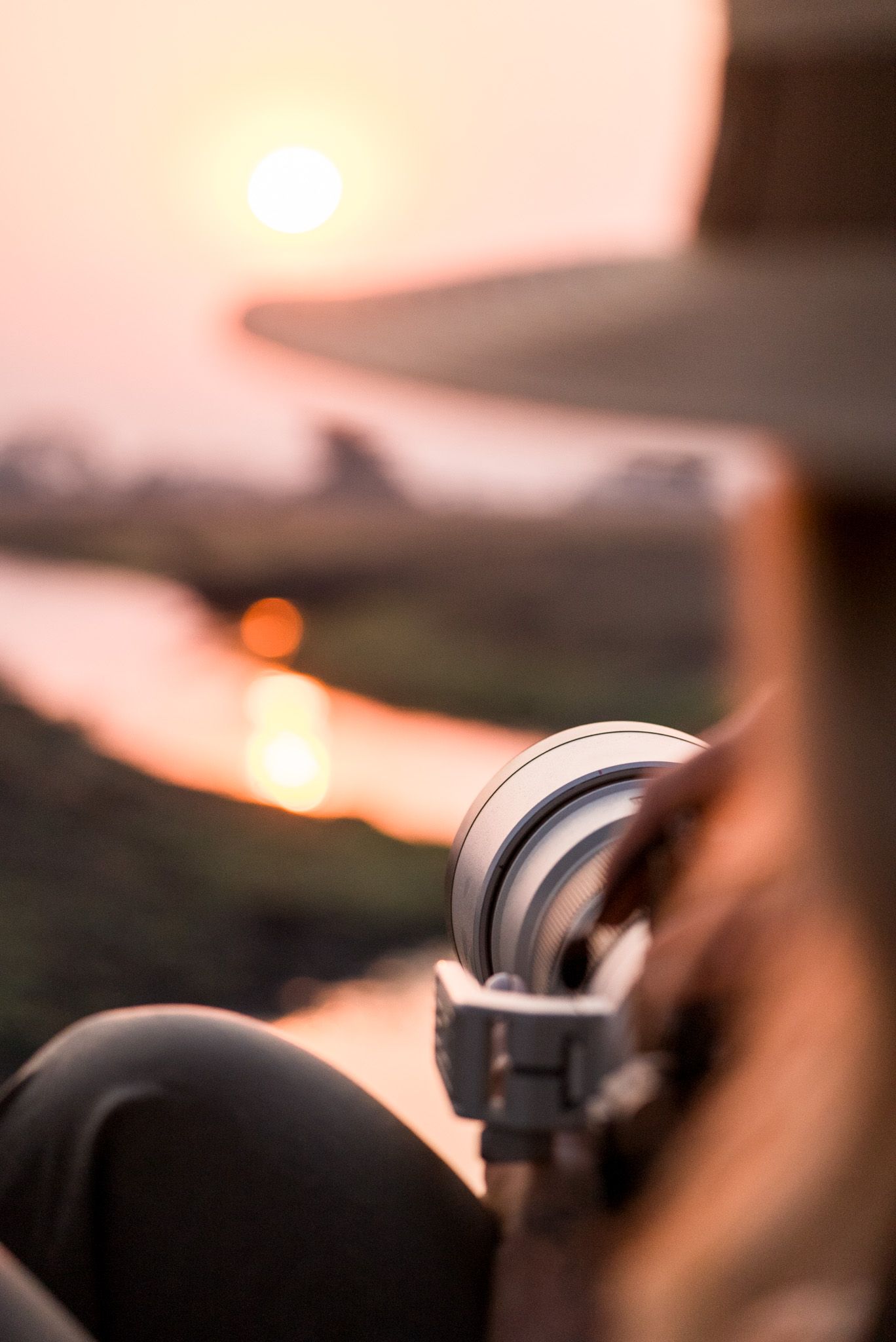 Closeup shot of camera equipment with silhouetted dials and buttons against a warm orange sunset background.