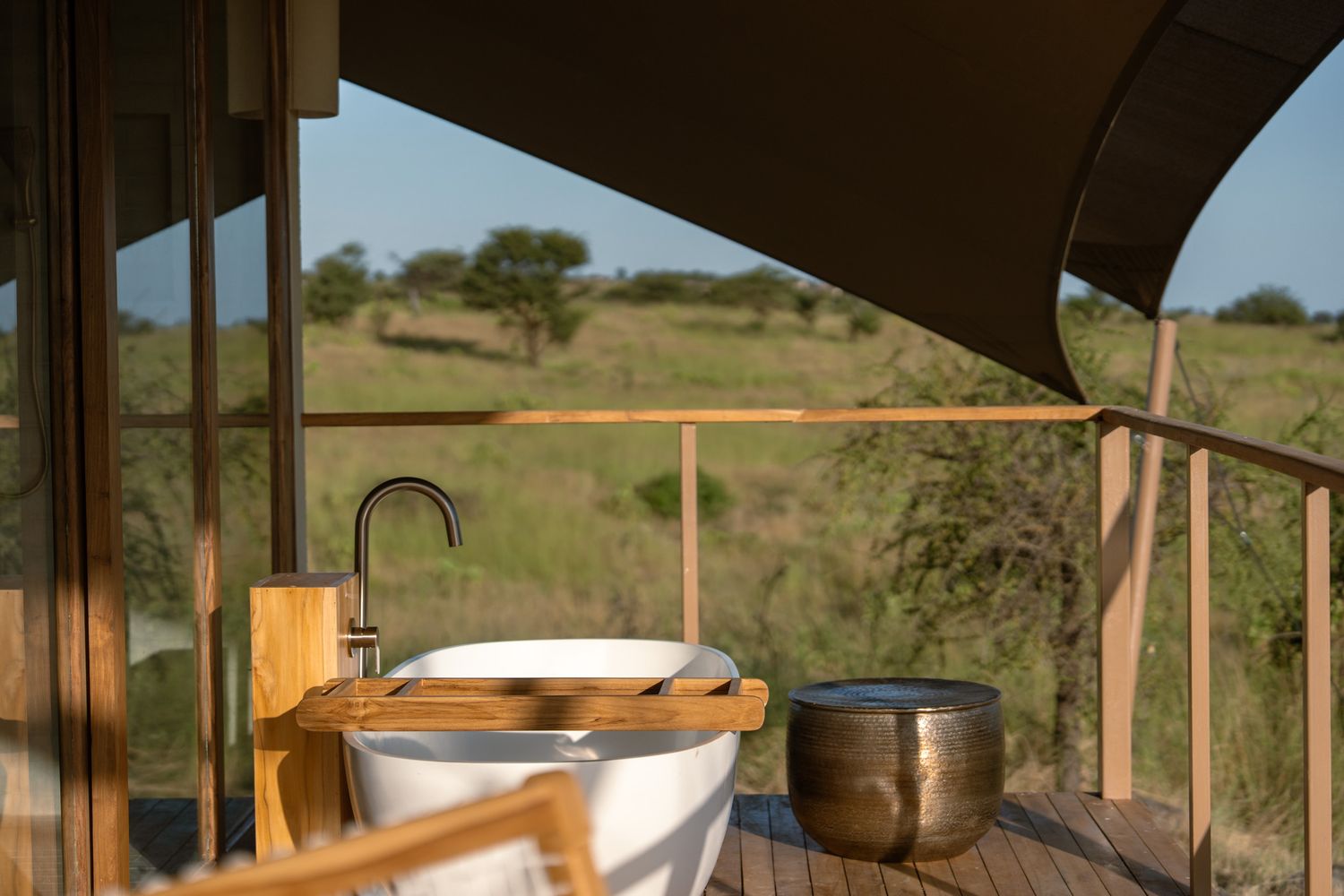 Outdoor bathtub on wooden deck overlooking African savanna landscape.