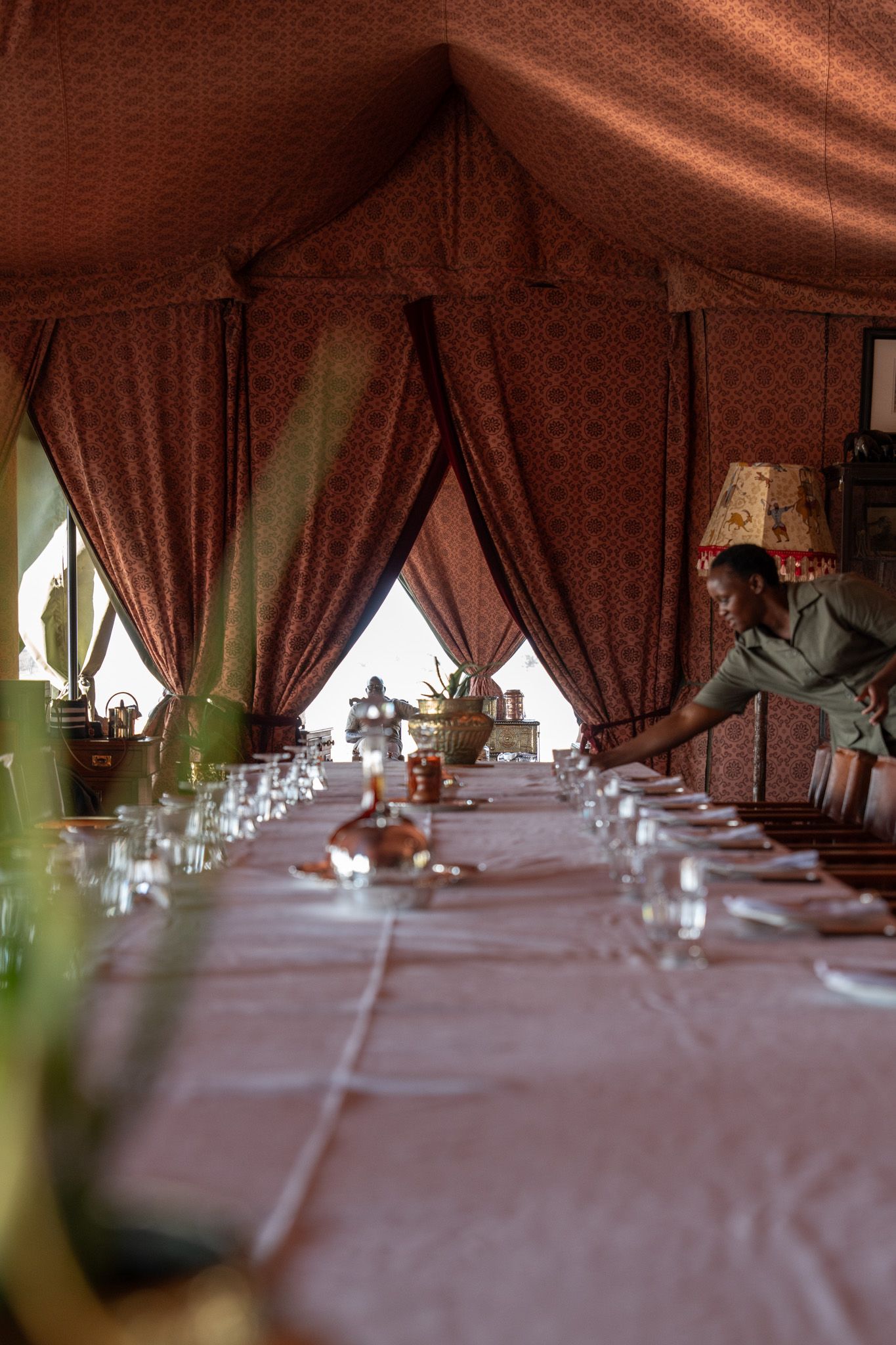 Elegant safari tent interior with long dining table and draped fabric walls.
