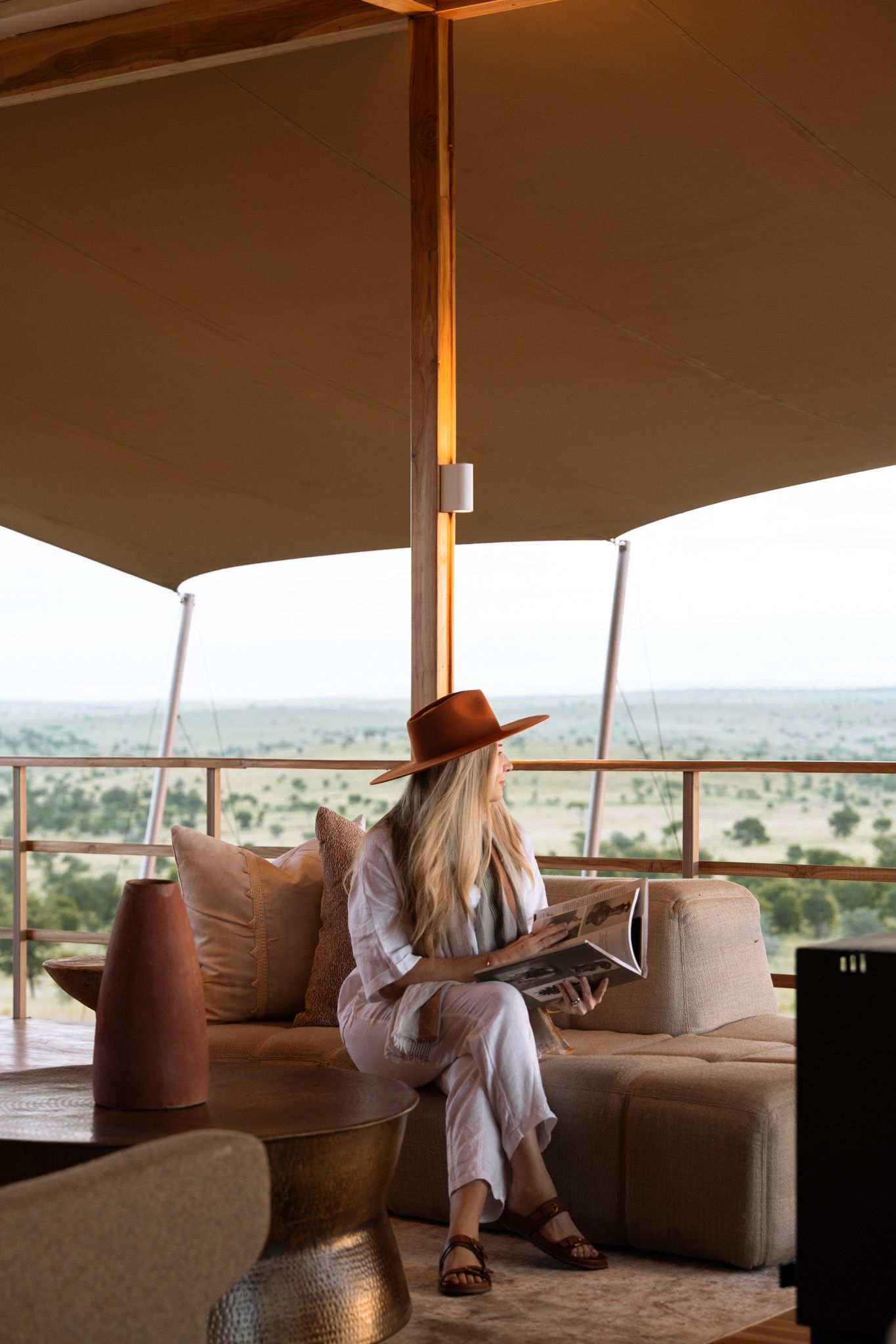 Safari-style lounge area with brown hat and comfortable seating overlooking savanna landscape.