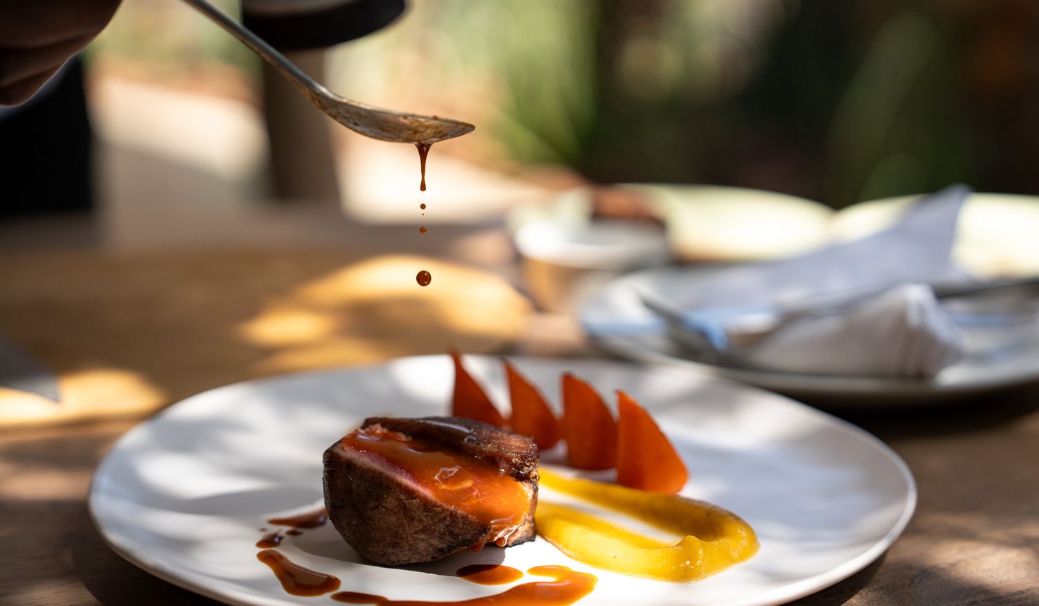 Close-up of dessert plate with chocolate cake and caramel sauce being drizzled.