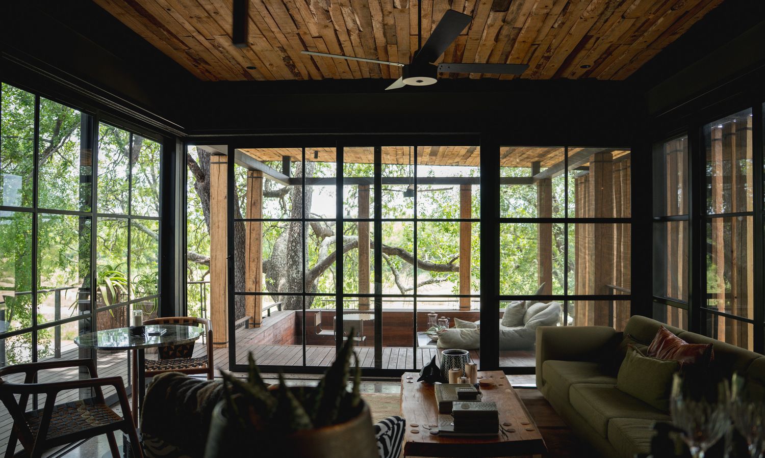 Floor-to-ceiling windows in a modern lodge living space offering panoramic views of nature.