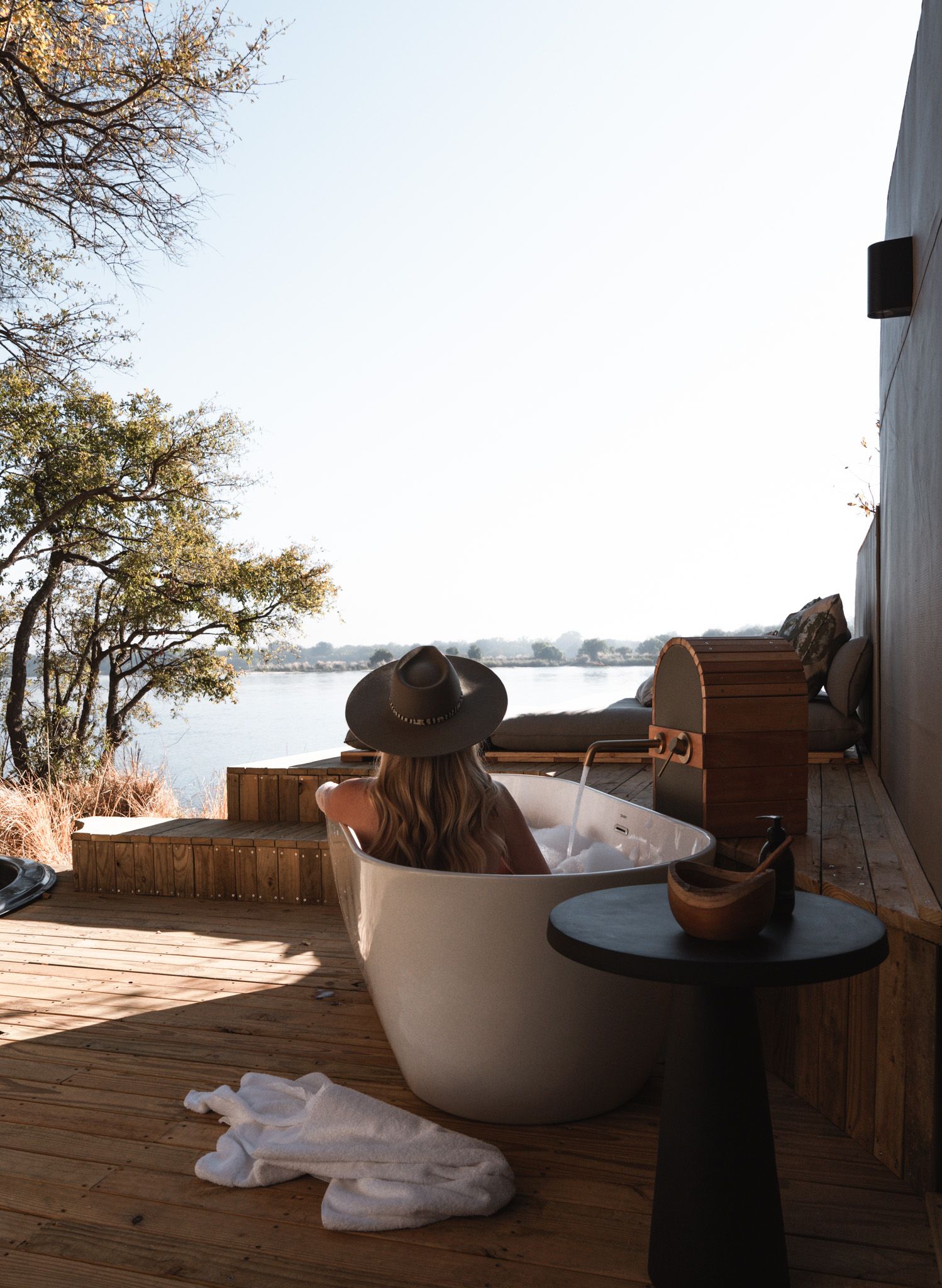 Relaxing outdoor bath setup on wooden deck overlooking scenic lake view.