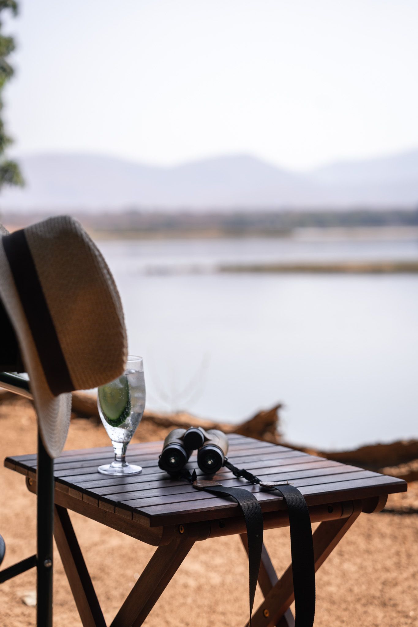 Outdoor lounge chairs overlooking a serene lake view with mountains in the background.