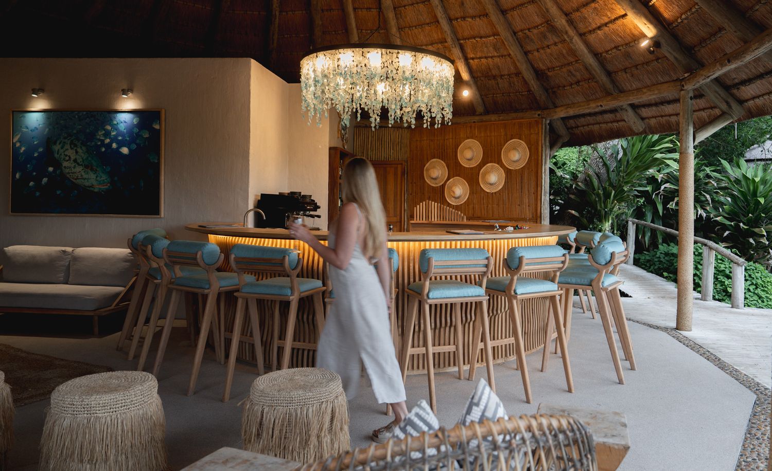 Elegant open-air restaurant with thatched roof and natural wood furnishings overlooking lush surroundings.