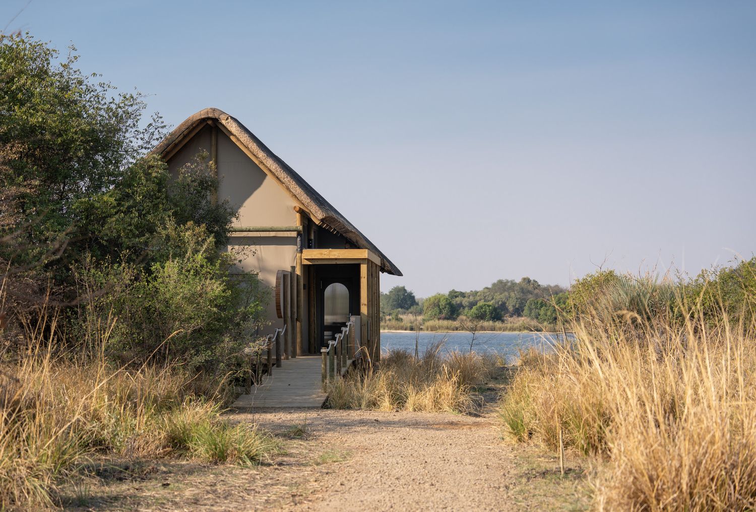 Small rustic cabin nestled among tall grass near a serene lake.