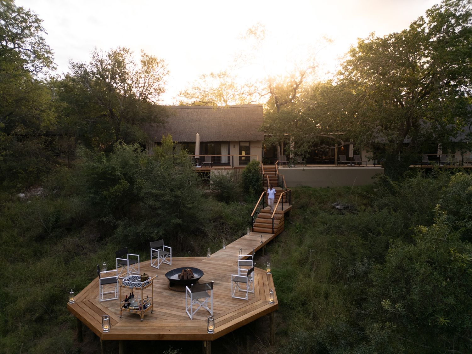 Elevated deck with outdoor furniture overlooking a rustic lodge at dusk.