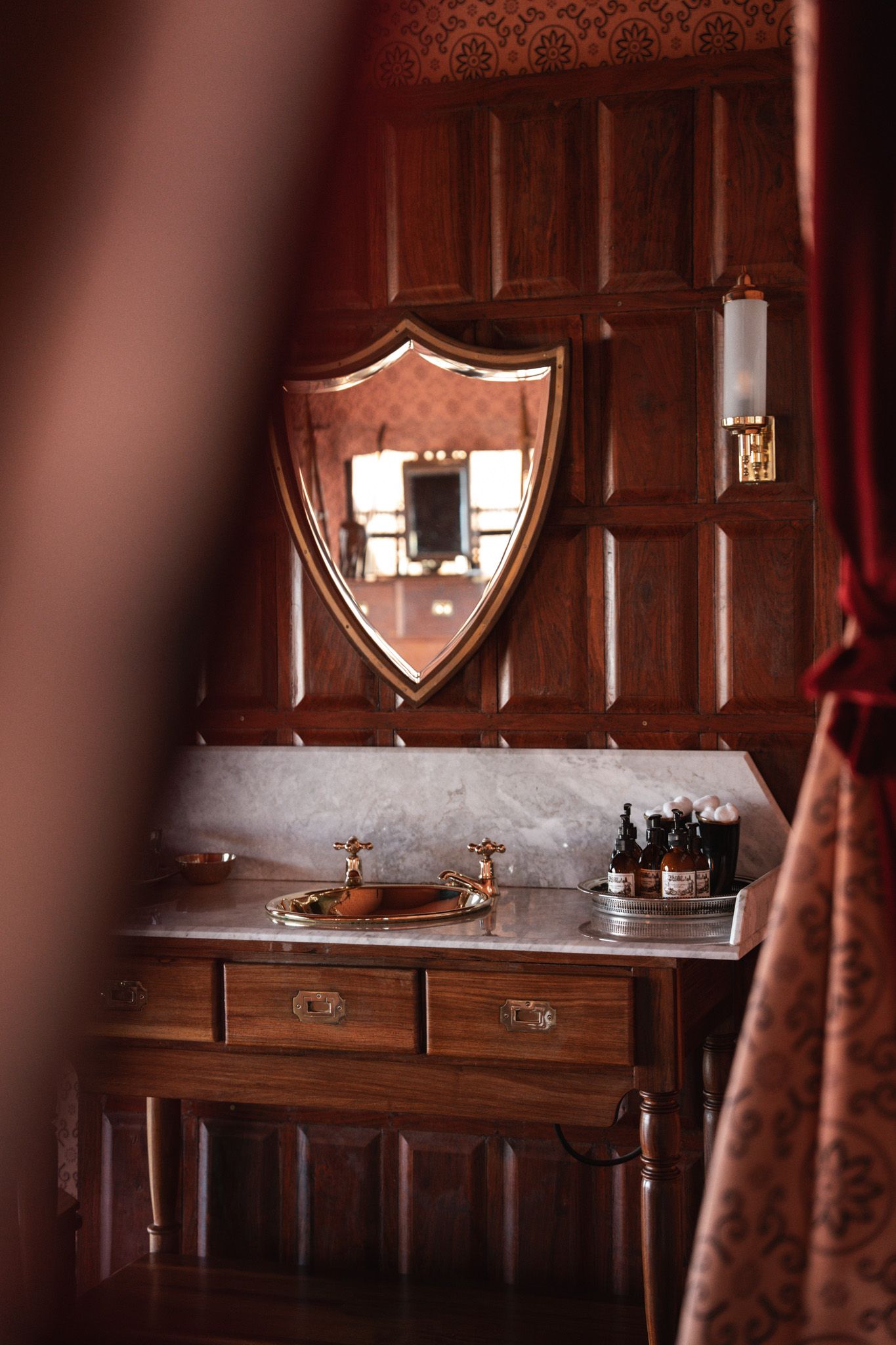 Vintage wooden vanity with ornate mirrors and decorative items in warm lighting.