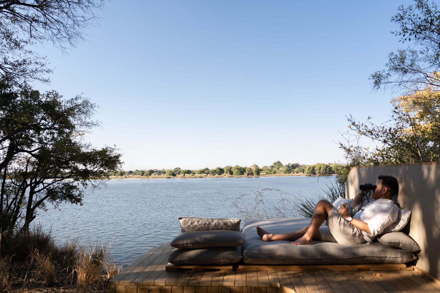 Scenic lakeside view with lounge area at sunset overlooking calm waters.
