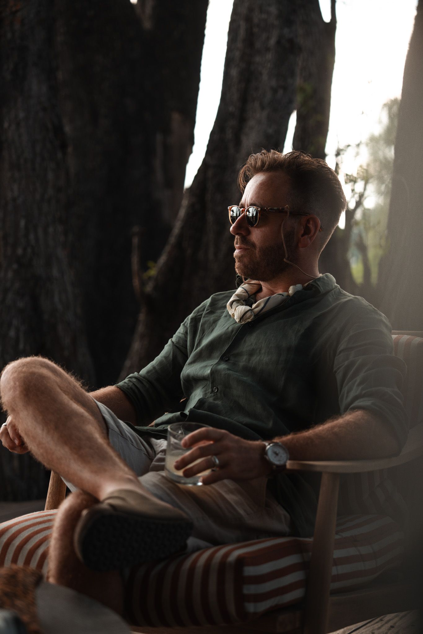 Person relaxing in casual attire on an outdoor chair during golden hour.