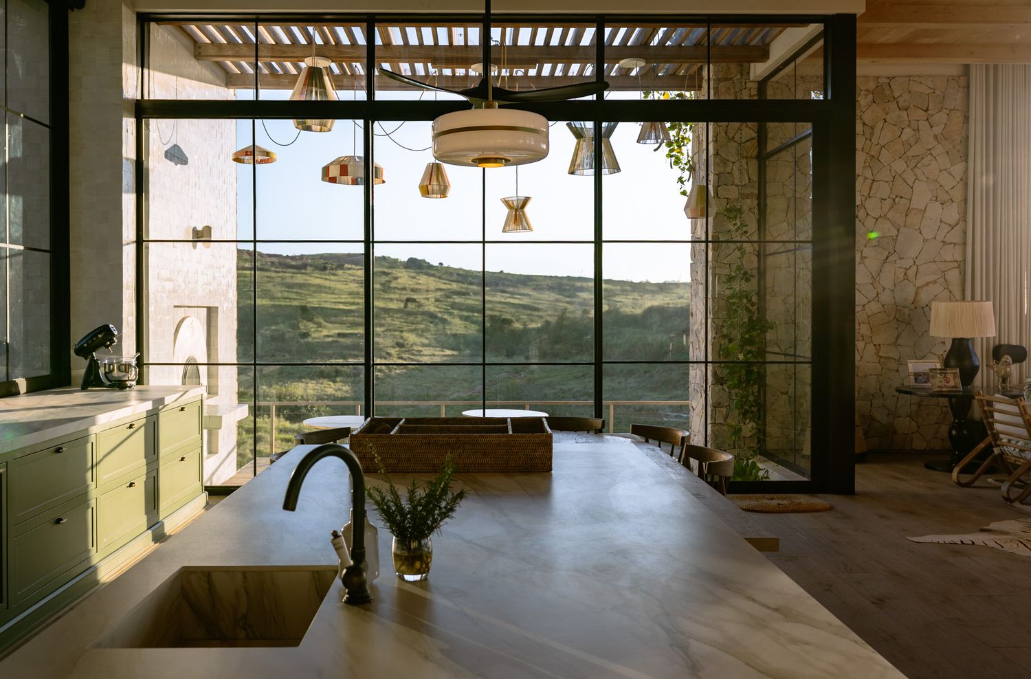Contemporary kitchen with large windows overlooking scenic landscape and pendant lighting.