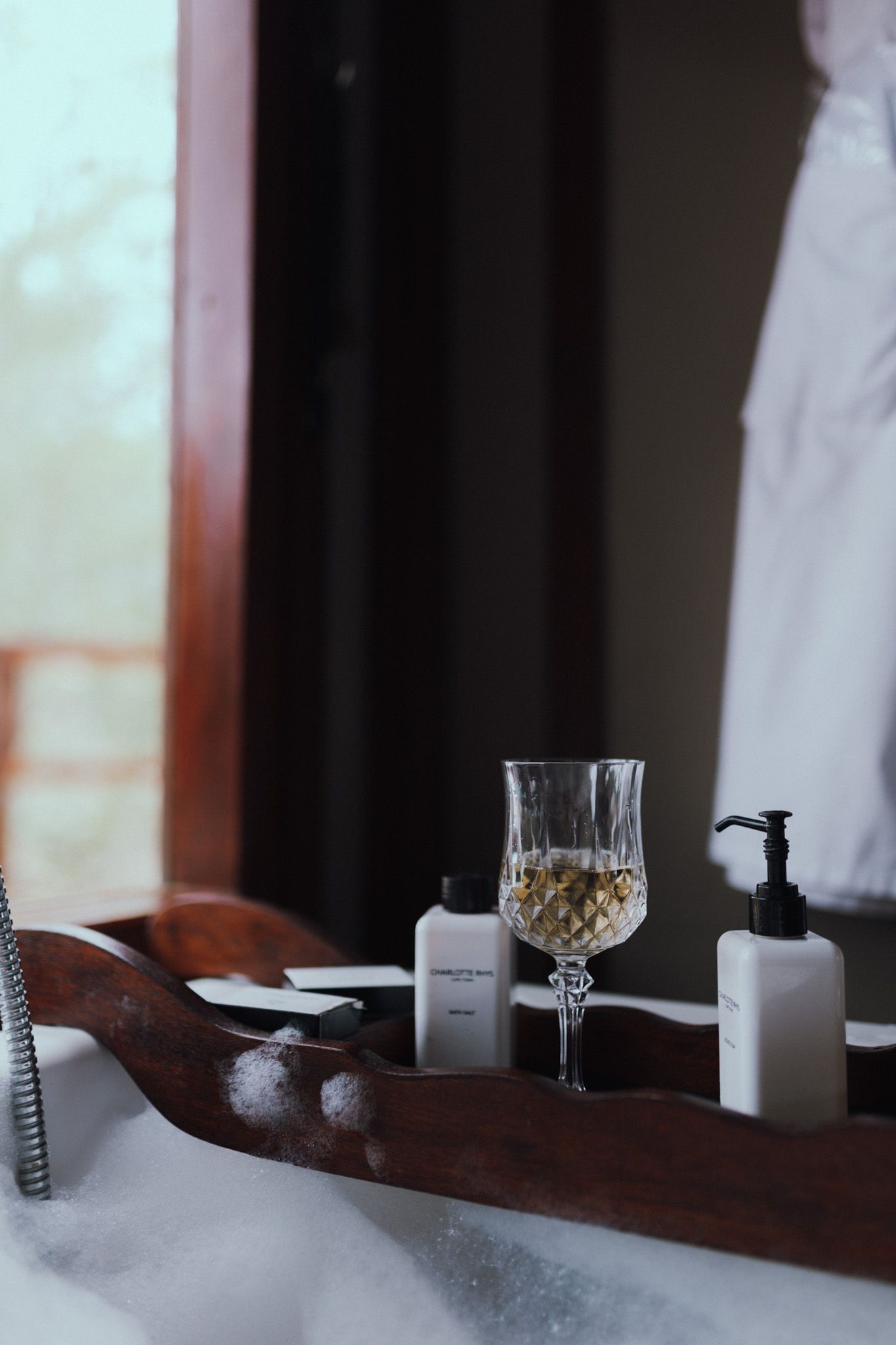 Crystal glasses and dining essentials arranged on wooden surface with soft natural lighting.