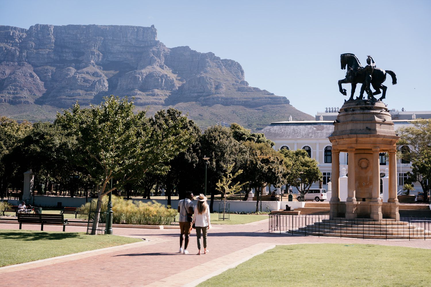 Desert landscape with mountain cliffs and a decorative statue silhouetted against blue sky.