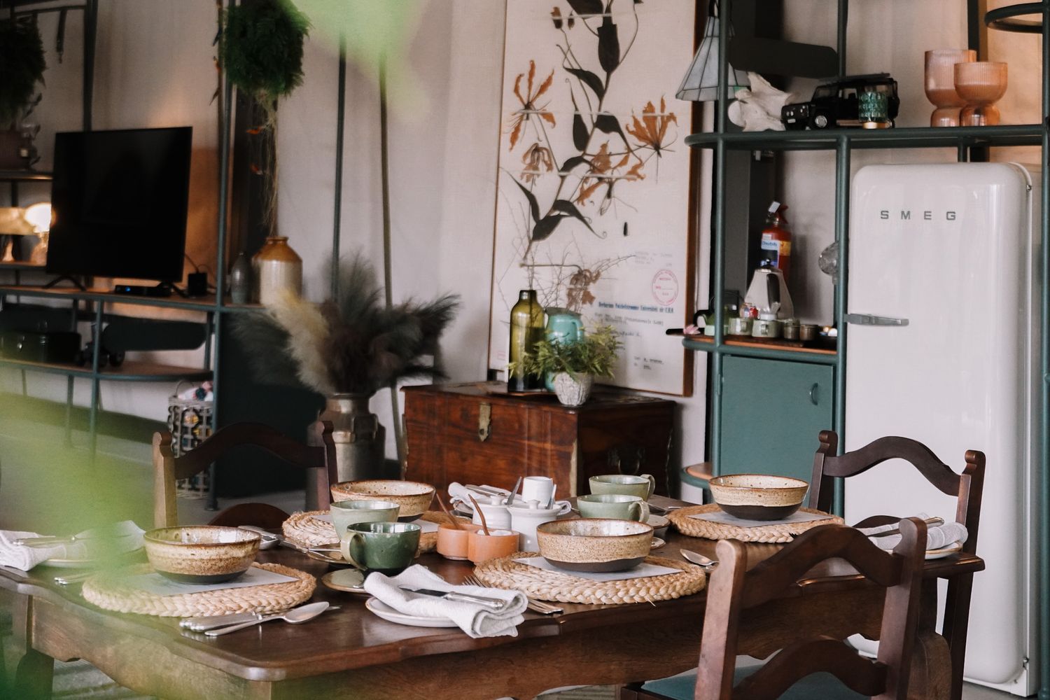 Mid-century dining room with vintage furniture, wall art, and arranged table settings.