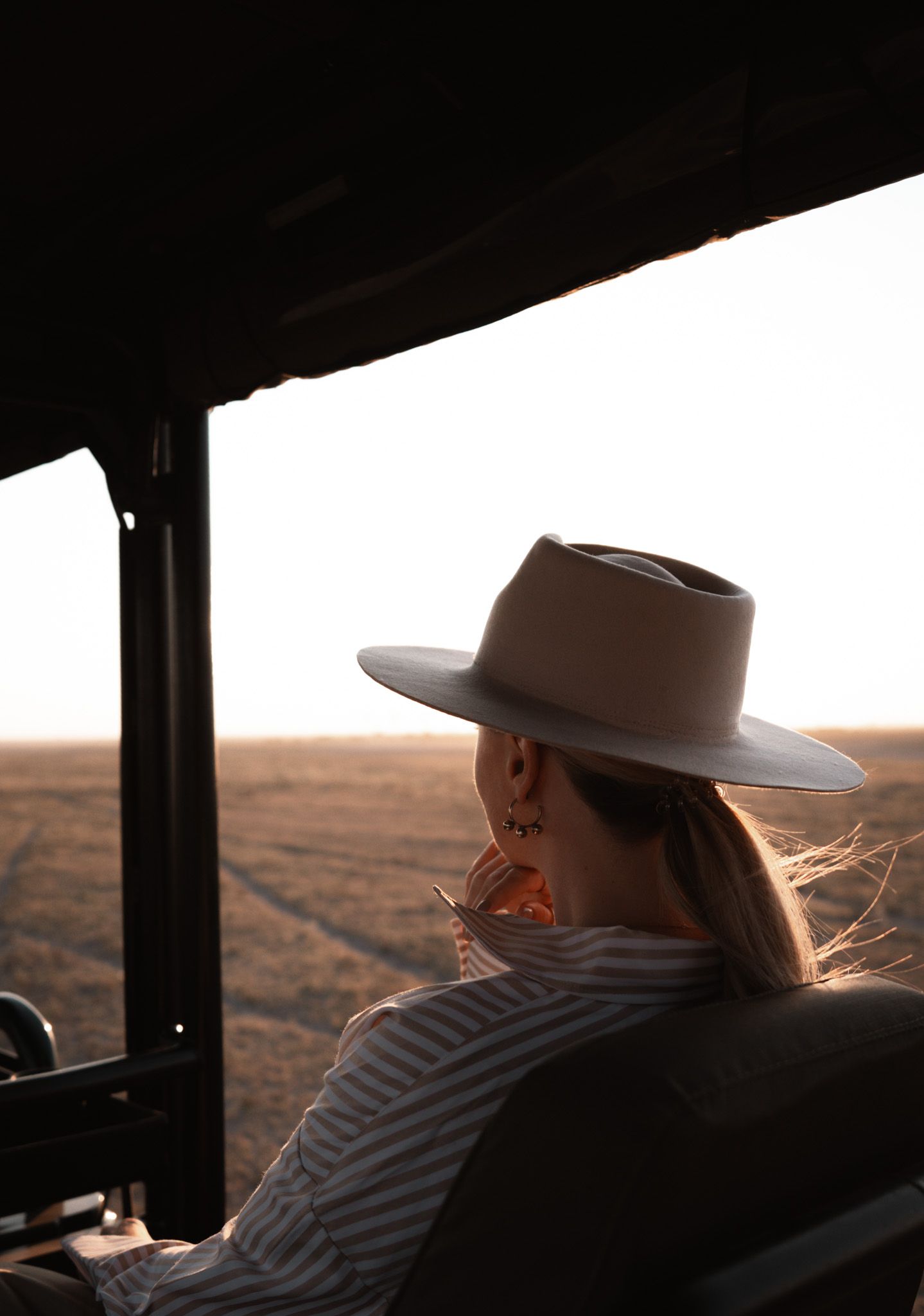 Silhouette view through a vehicle window during golden hour in a rural landscape.